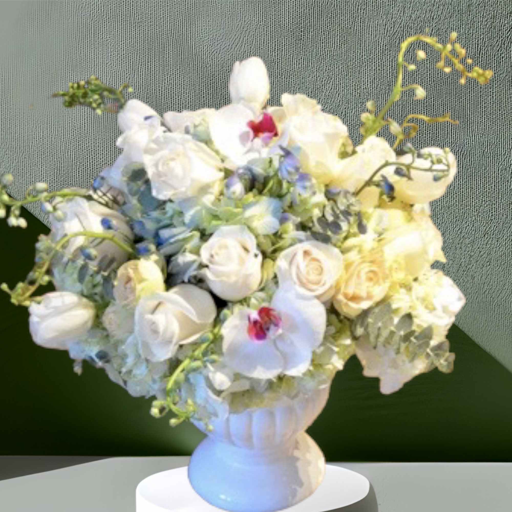 A calming mix of baby blue hydrangea, white roses, white tulips, orchids