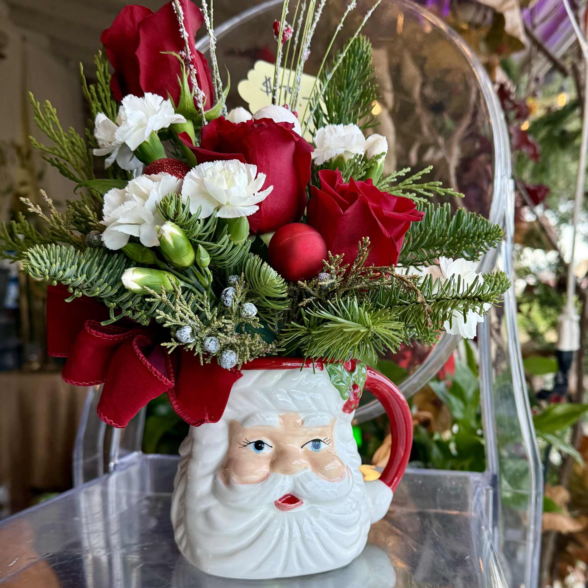 A Festive Mug of Santa&#039;s face, Red roses, mini carnations, pines greenery