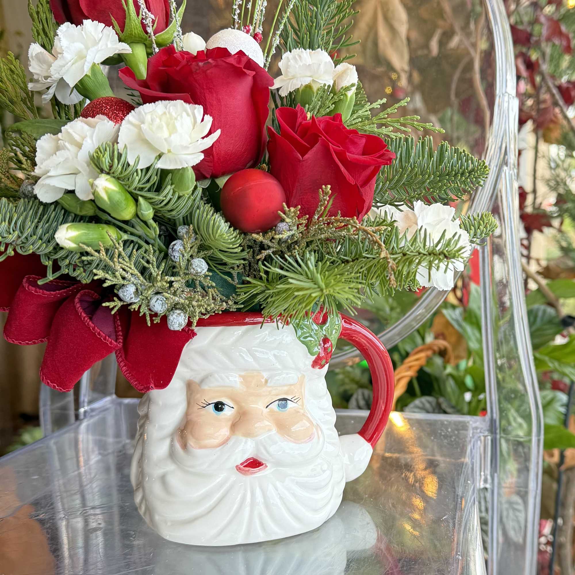 A Festive Mug of Santa&#039;s face, Red roses, mini carnations, pines greenery