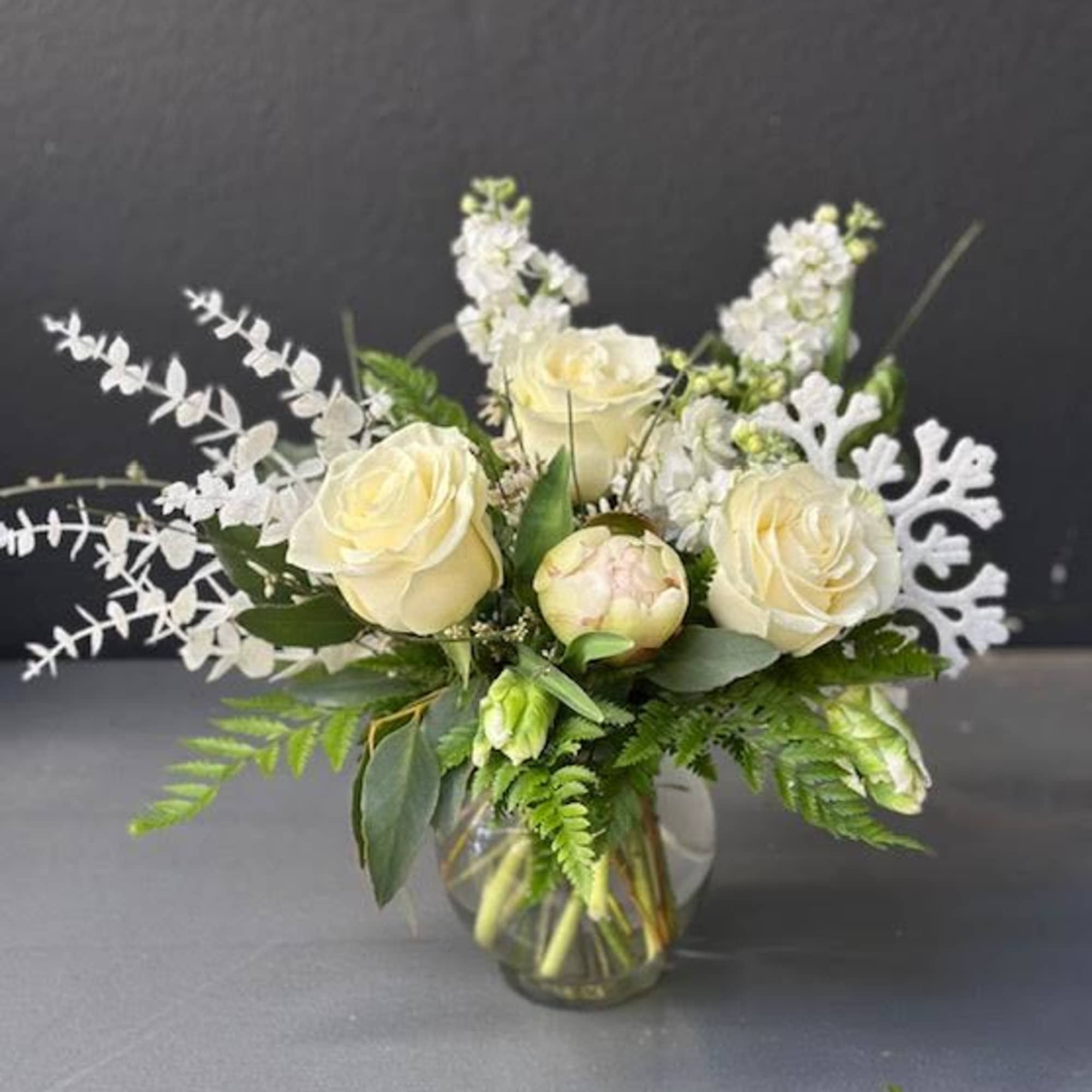 A beautiful winter time arrangement, designed using all white florals, roses, peonies