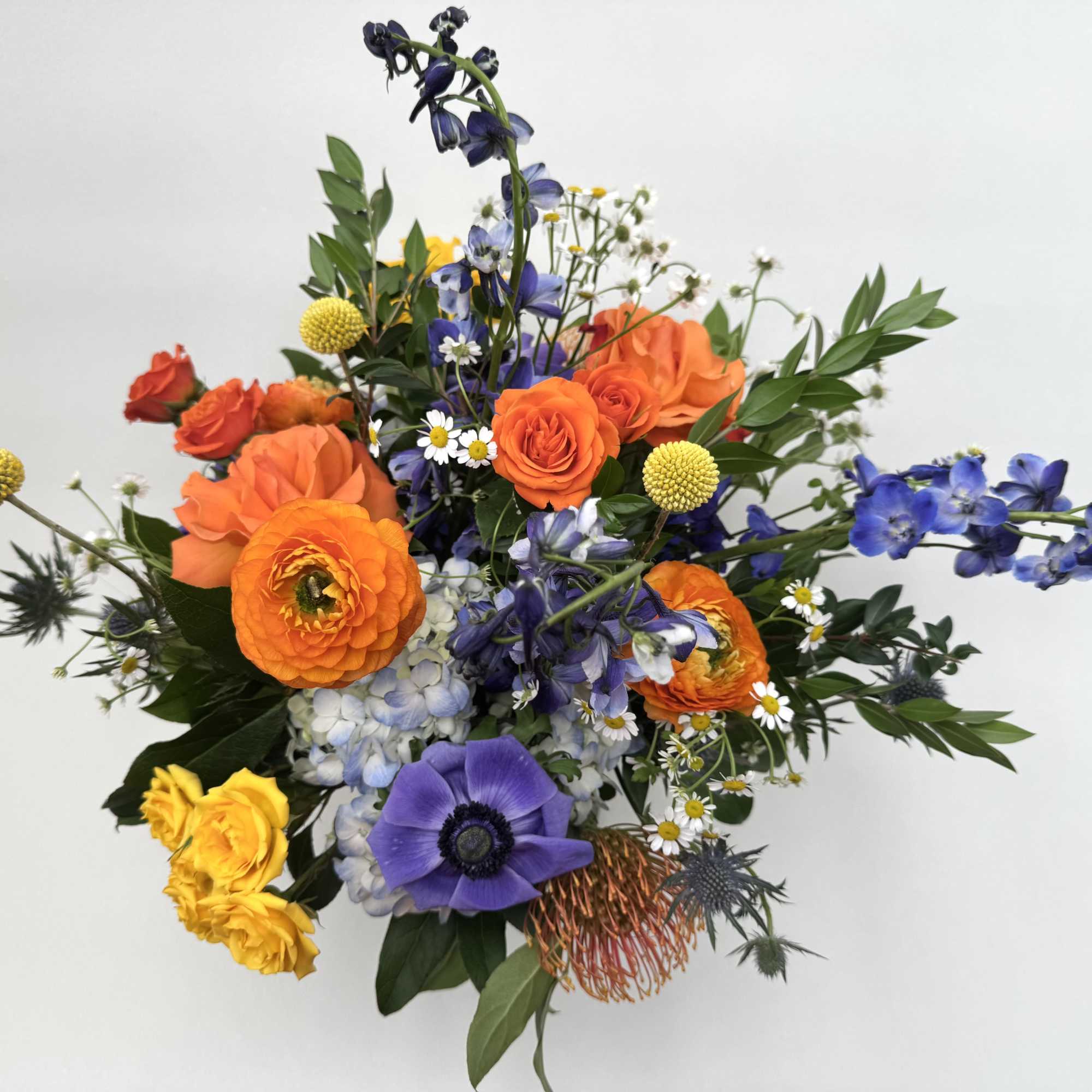 Neptune is a whimsical arrangement with blue, yellow and orange flowers that