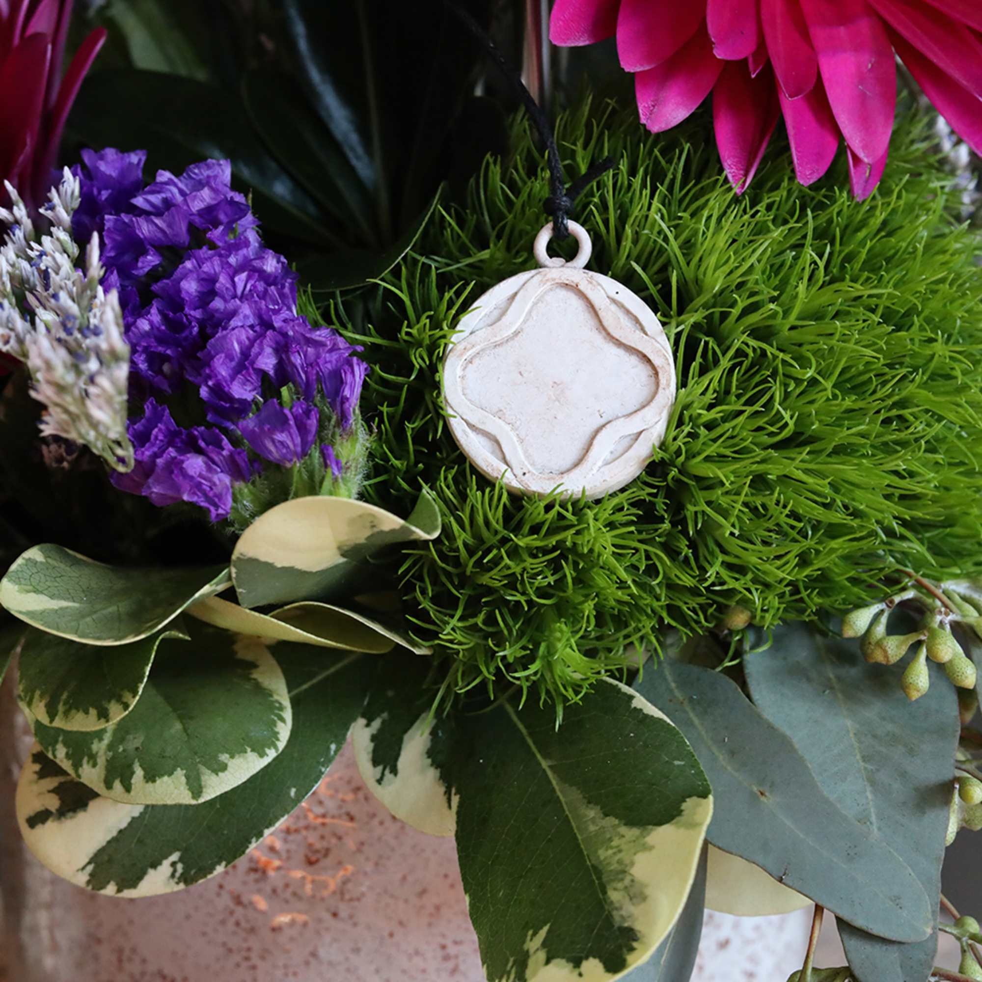 A gorgeous sympathy arrangement with a small hanging wind chime keepsake with