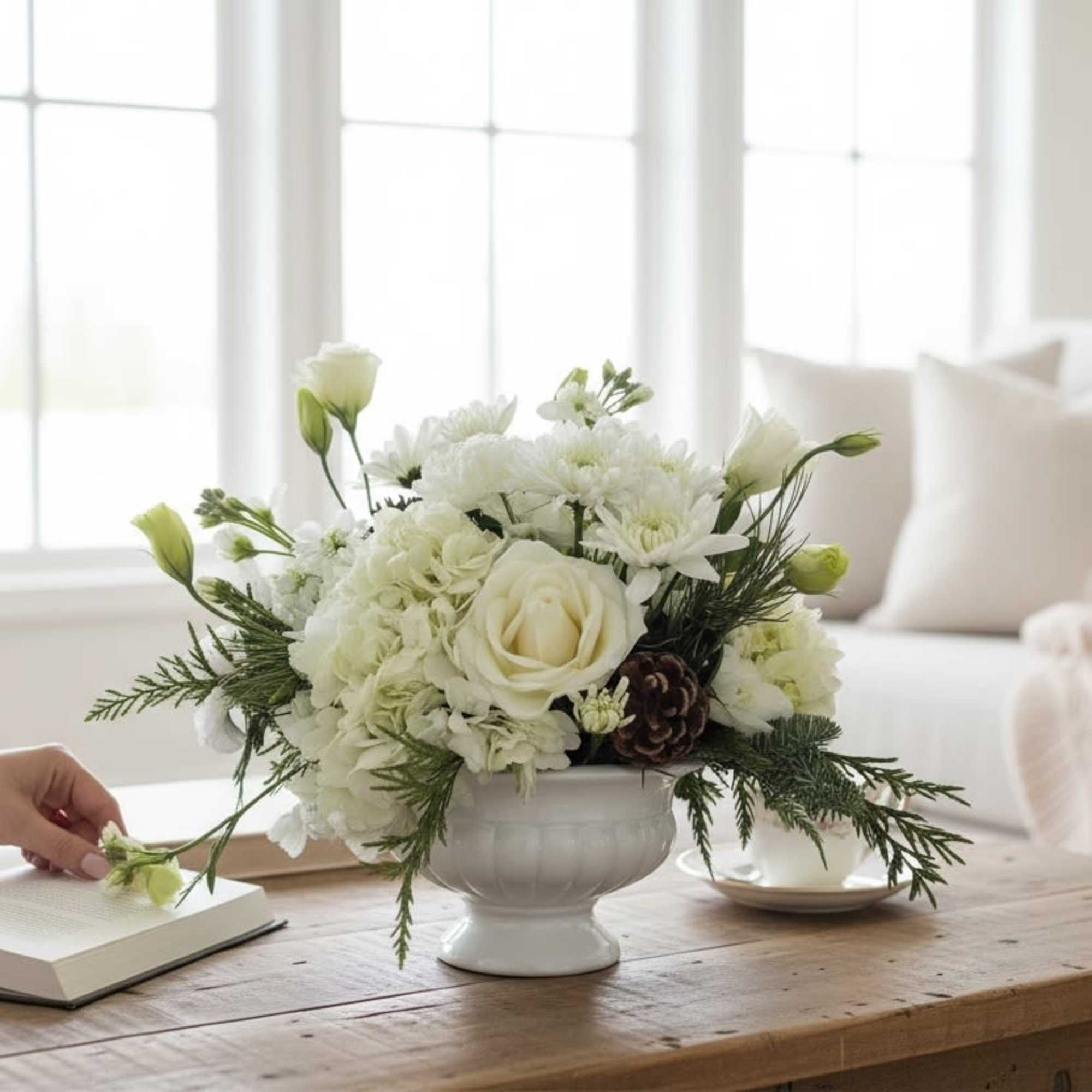A beautiful compote filled with assorted white flowers, pine cones and evergreens.