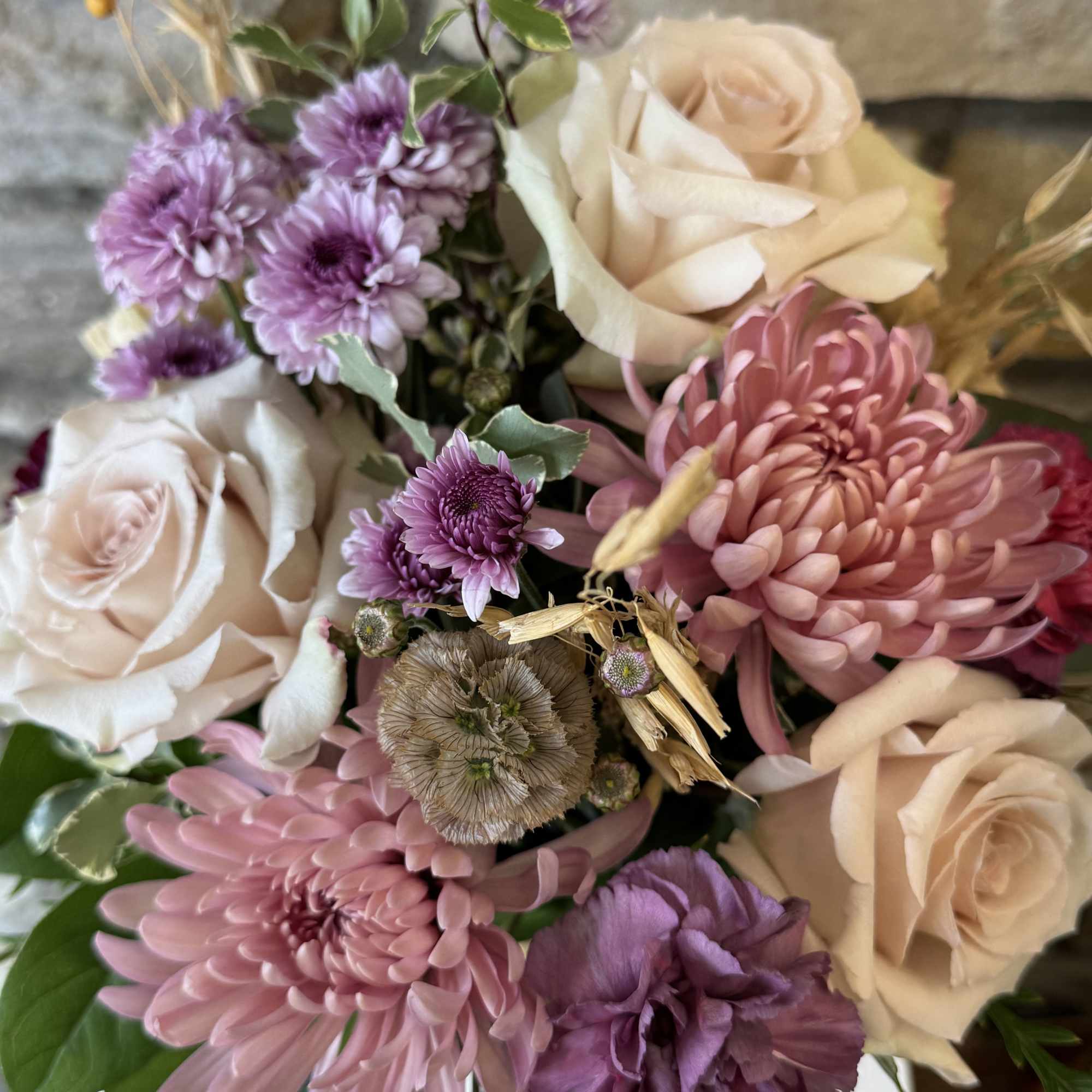 Muted colored roses, lavenders and purples bring this bouquet together for an
