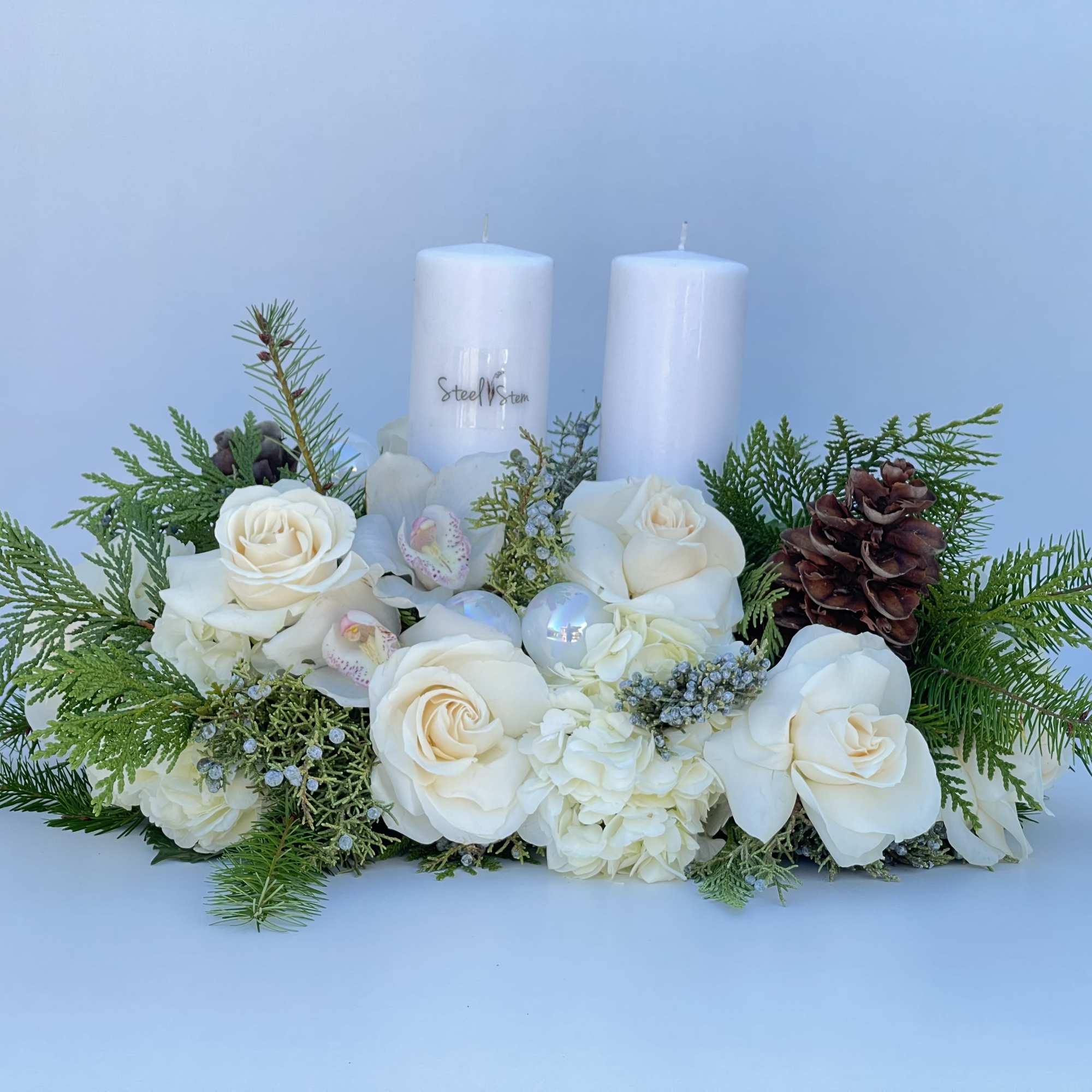Winter centerpiece arrangement with mix pine greens, pine cones, white rose, white