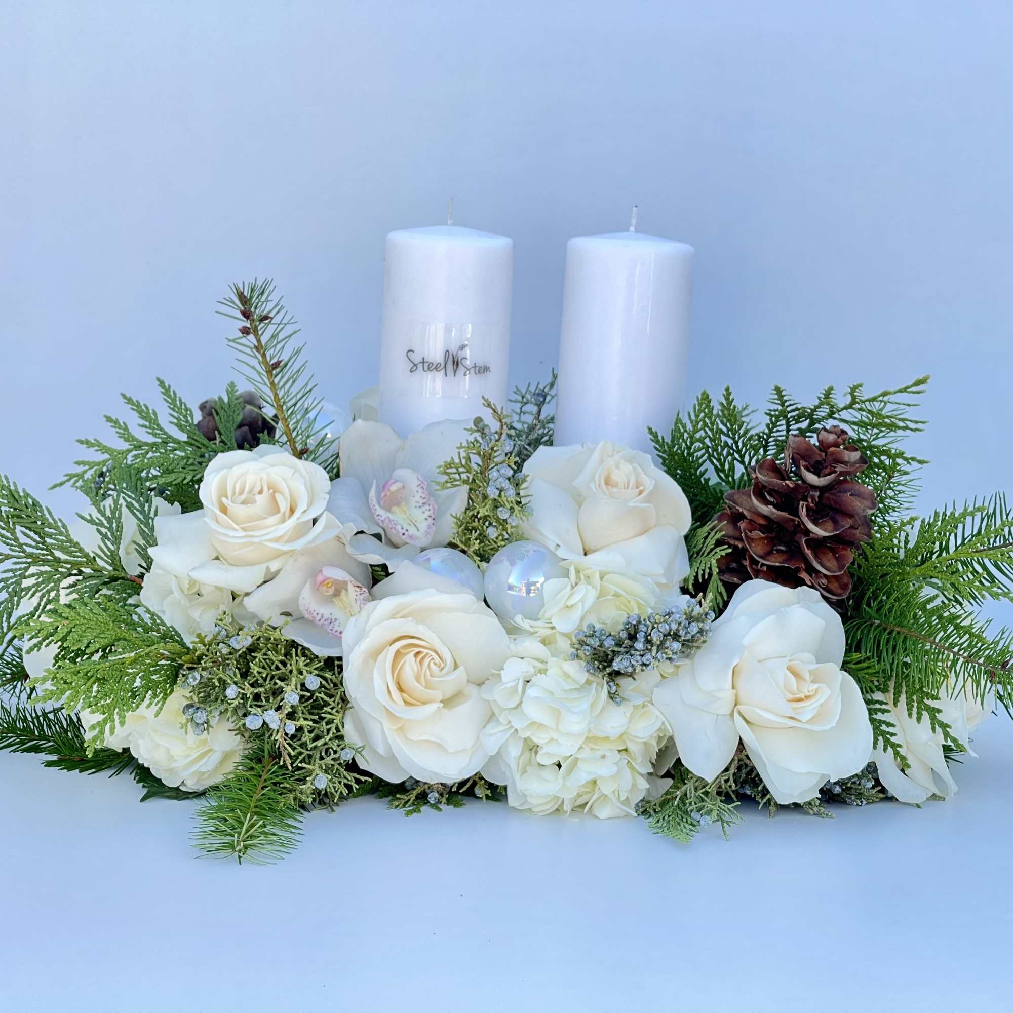 Winter centerpiece arrangement with mix pine greens, pine cones, white rose, white