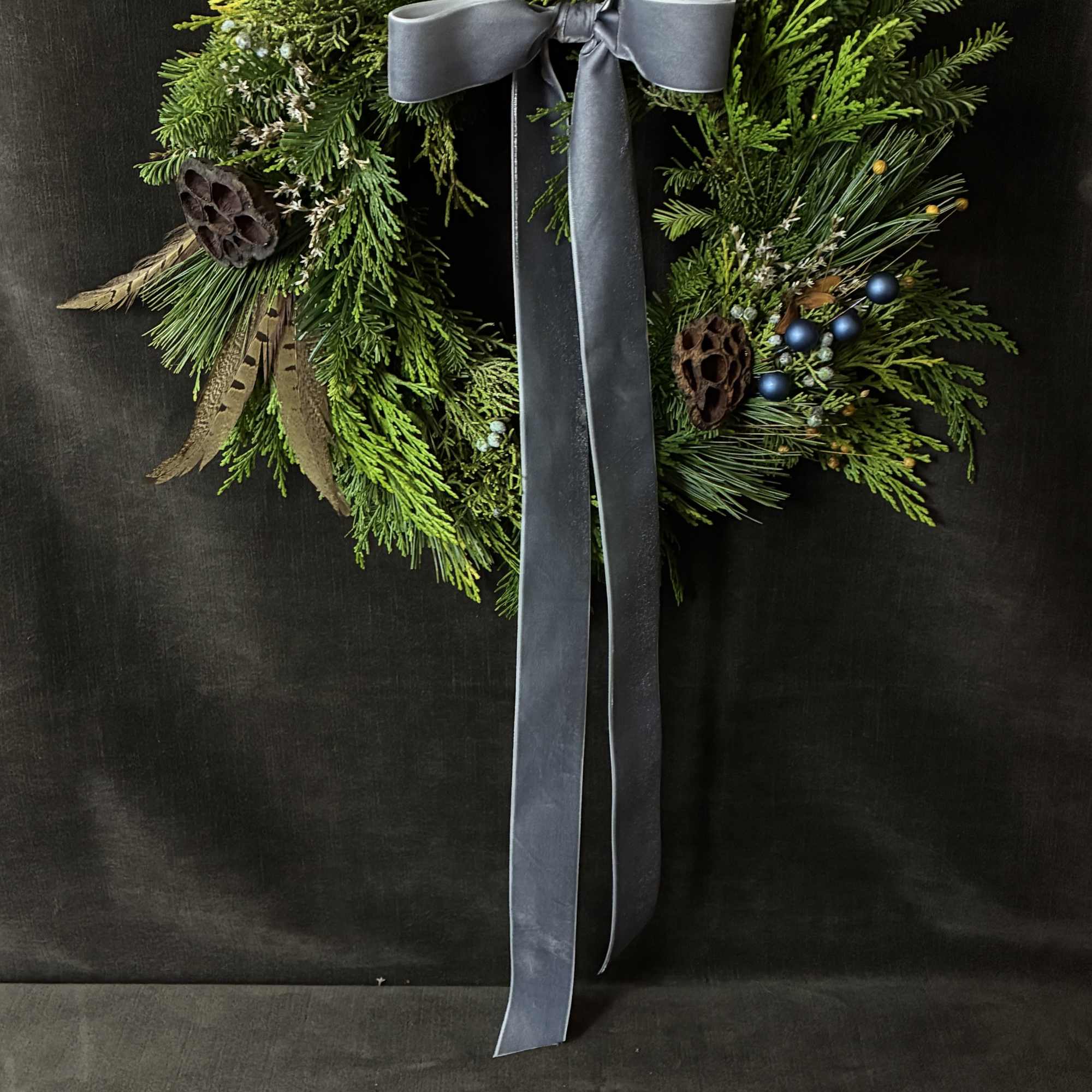 The Blue Jay Wreath blends steel-blue accents with fresh evergreens, juniper, and