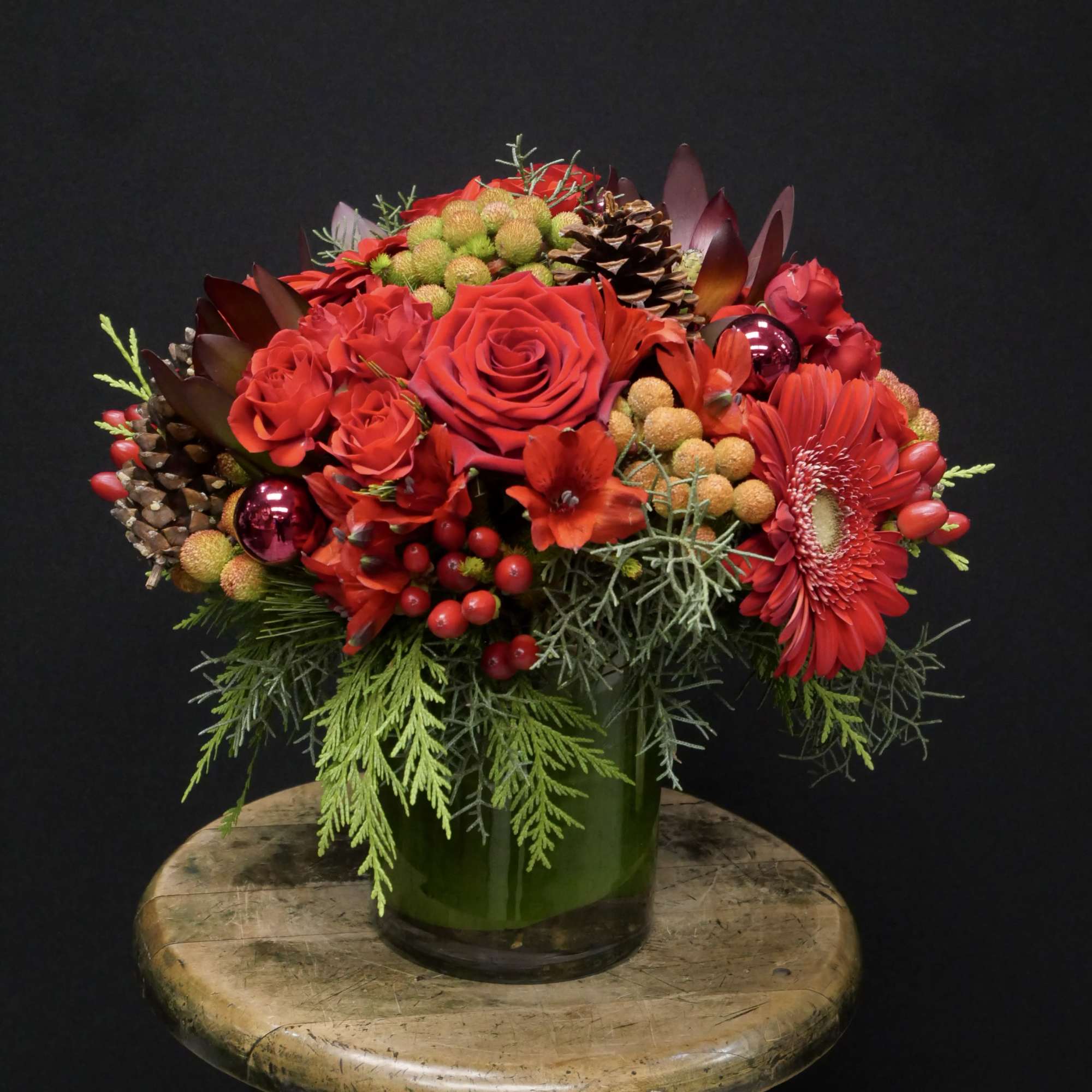 A beautiful assortment of different shades of reds, with holiday balls, pine
