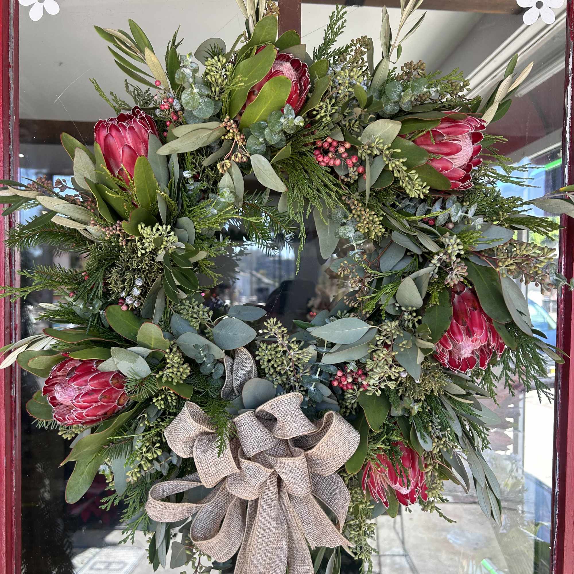 Seasonal Rustic flowers and greens arranged into a holiday wreath. (Hanger not
