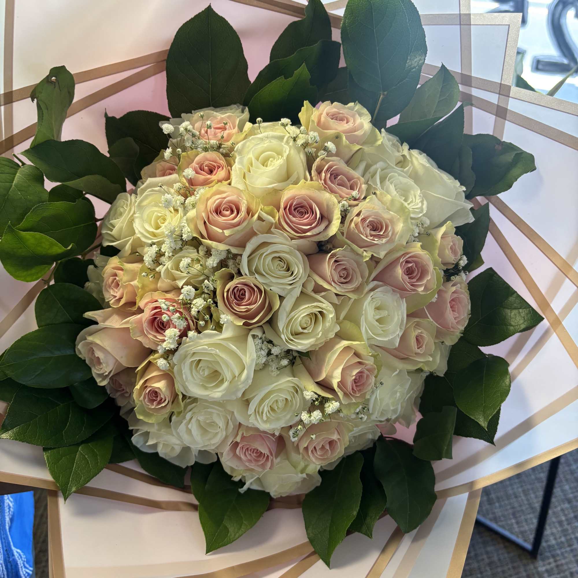 Fifty fresh roses in wrapping with lemon leaves  and baby breath