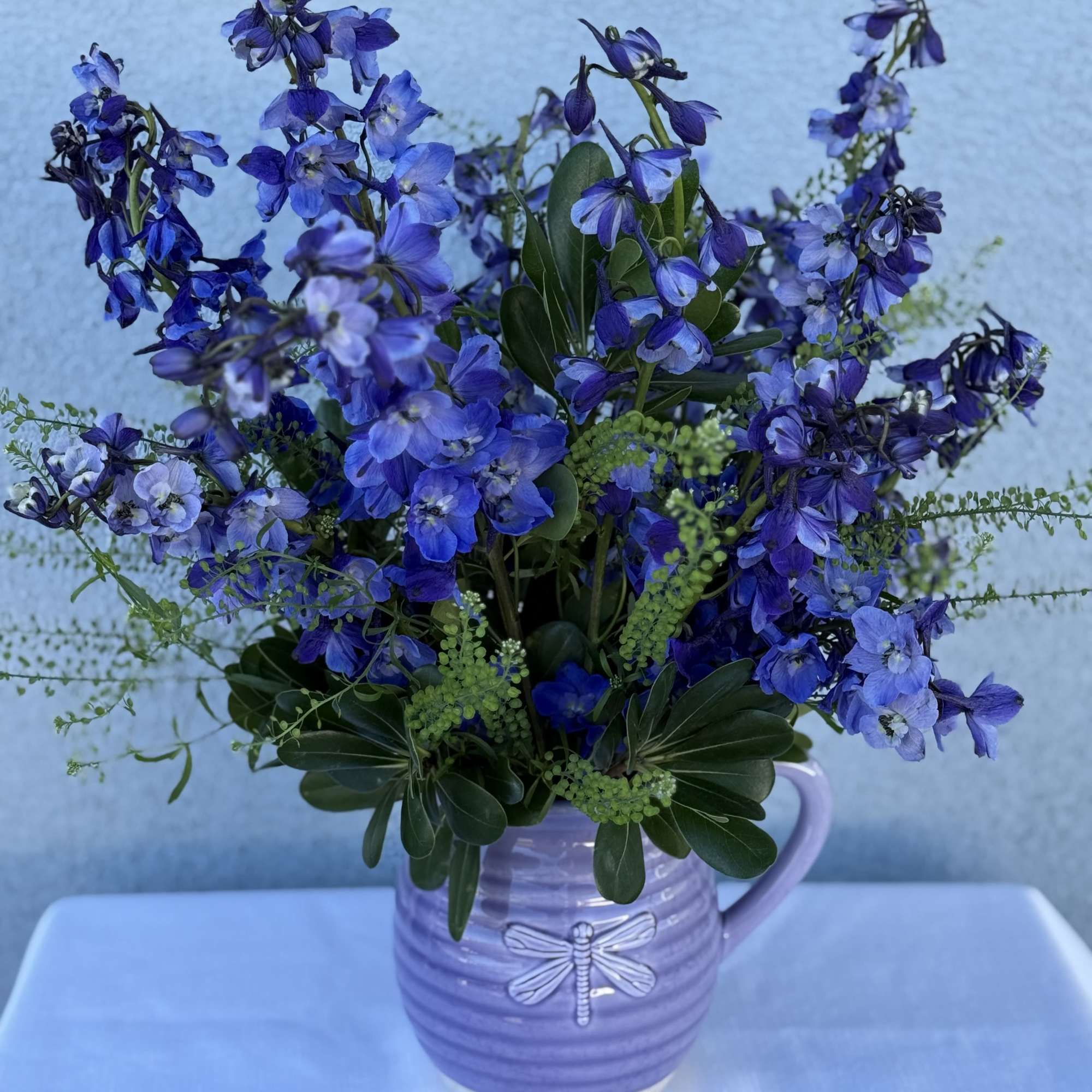 Dark blue/violet  delphinium lined flower bouquet with in season greenery. 

Arrangement
