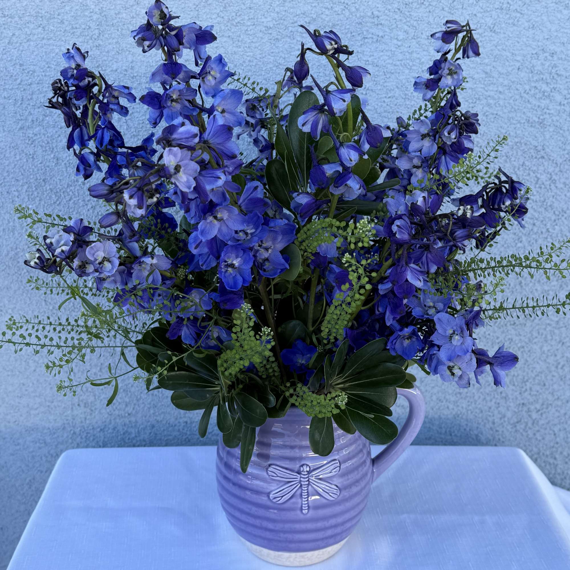 Dark blue/violet  delphinium lined flower bouquet with in season greenery. 

Arrangement