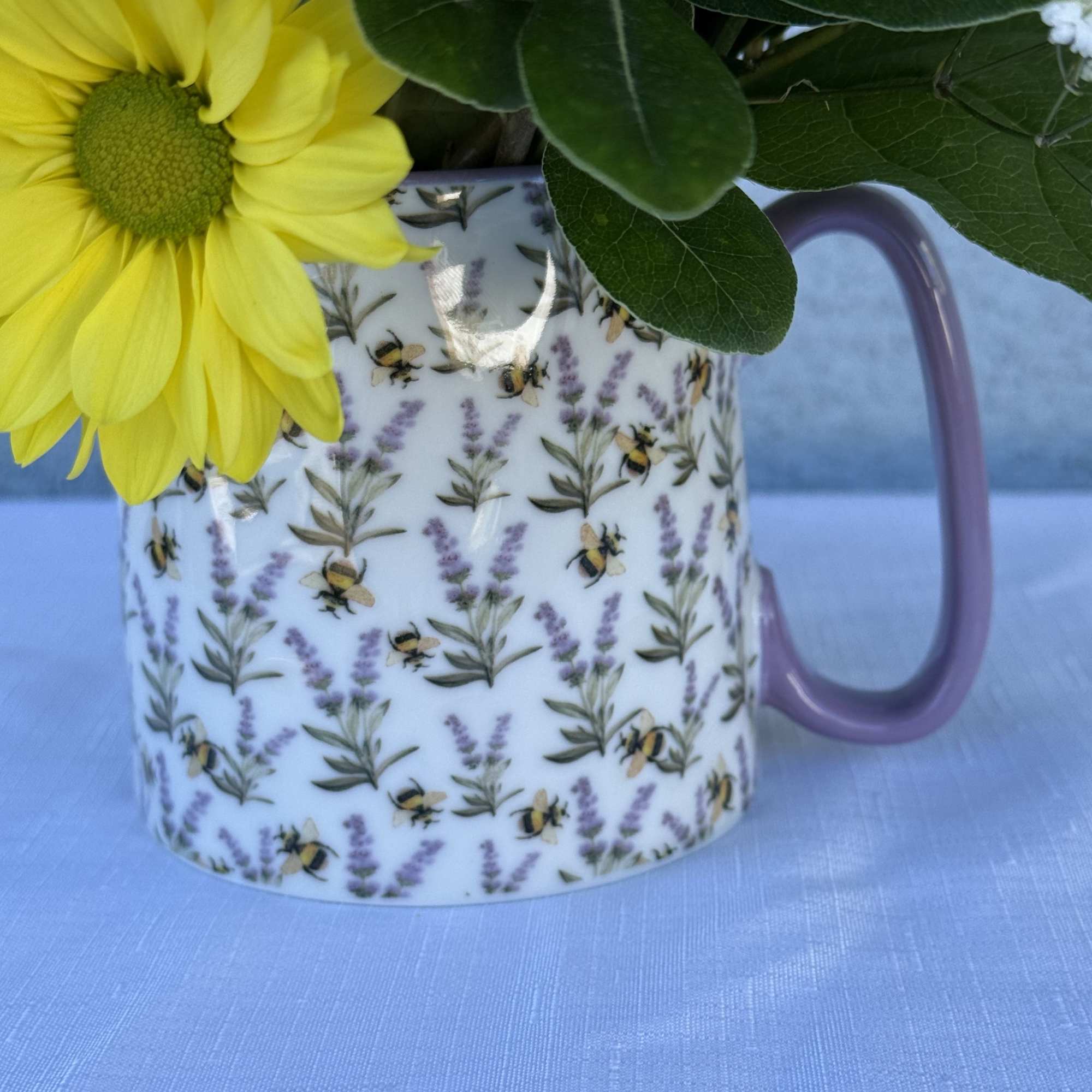 Bee coffee mug filled with daisies, sunflowers, roses and lisianthus.

Arrangement comes in