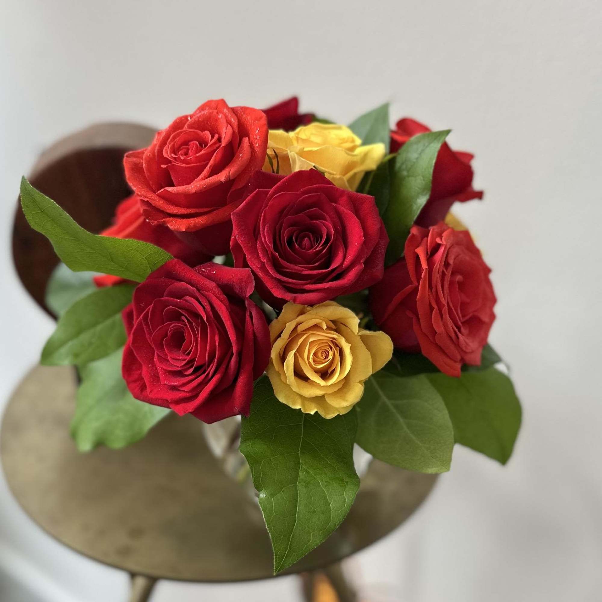 One dozen richly autumn colored roses, gathered in a fluted ivy bowl