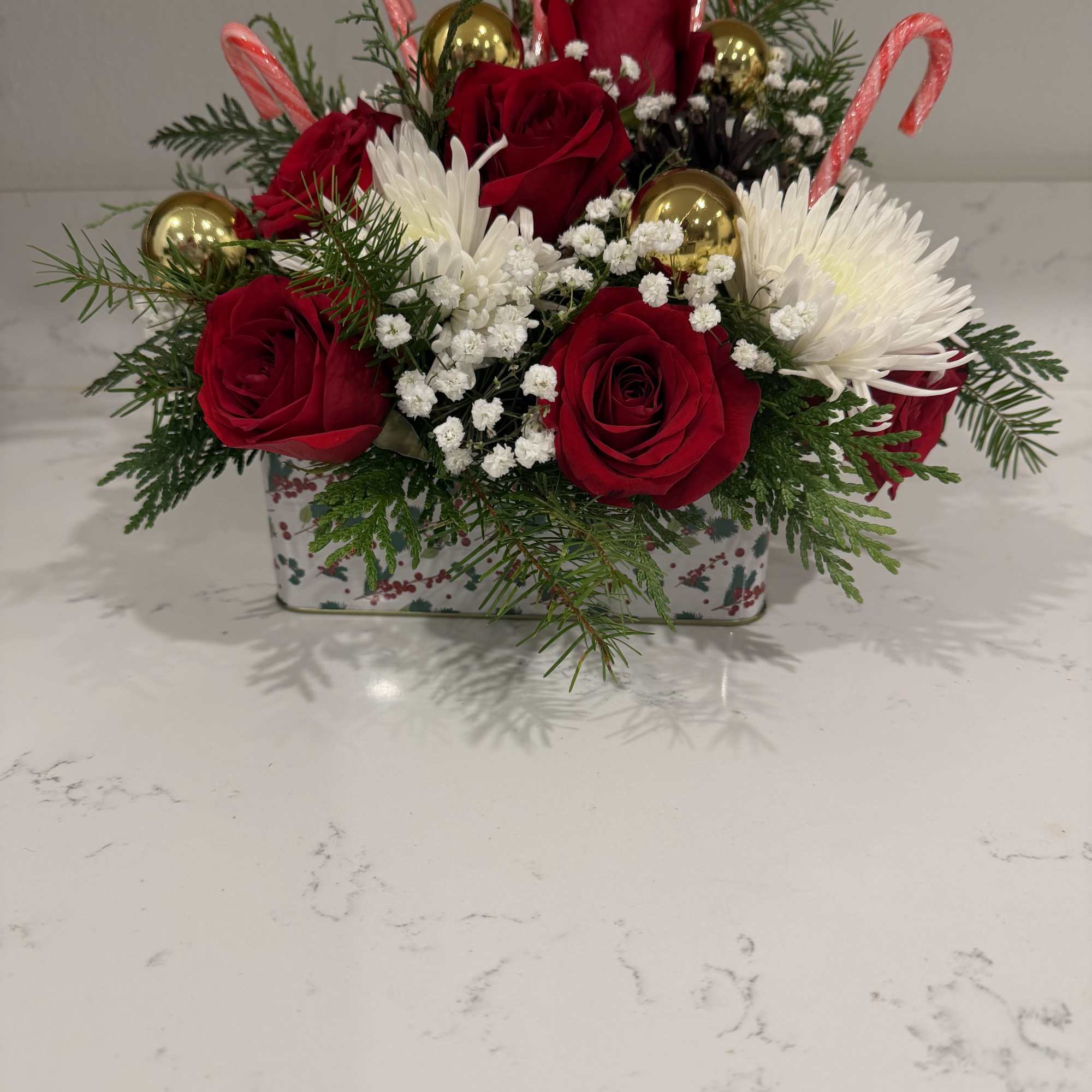 Fresh red roses, delicate baby&rsquo;s breath, and accented with candy canes and