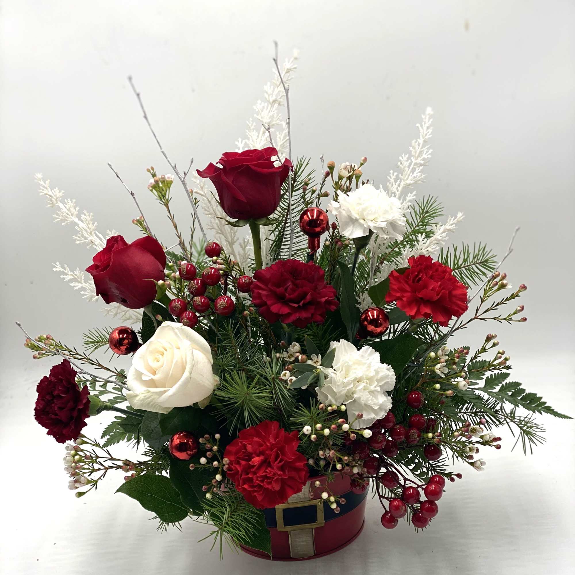 A festive holiday arrangement featuring rich red roses &amp; carnations paired with