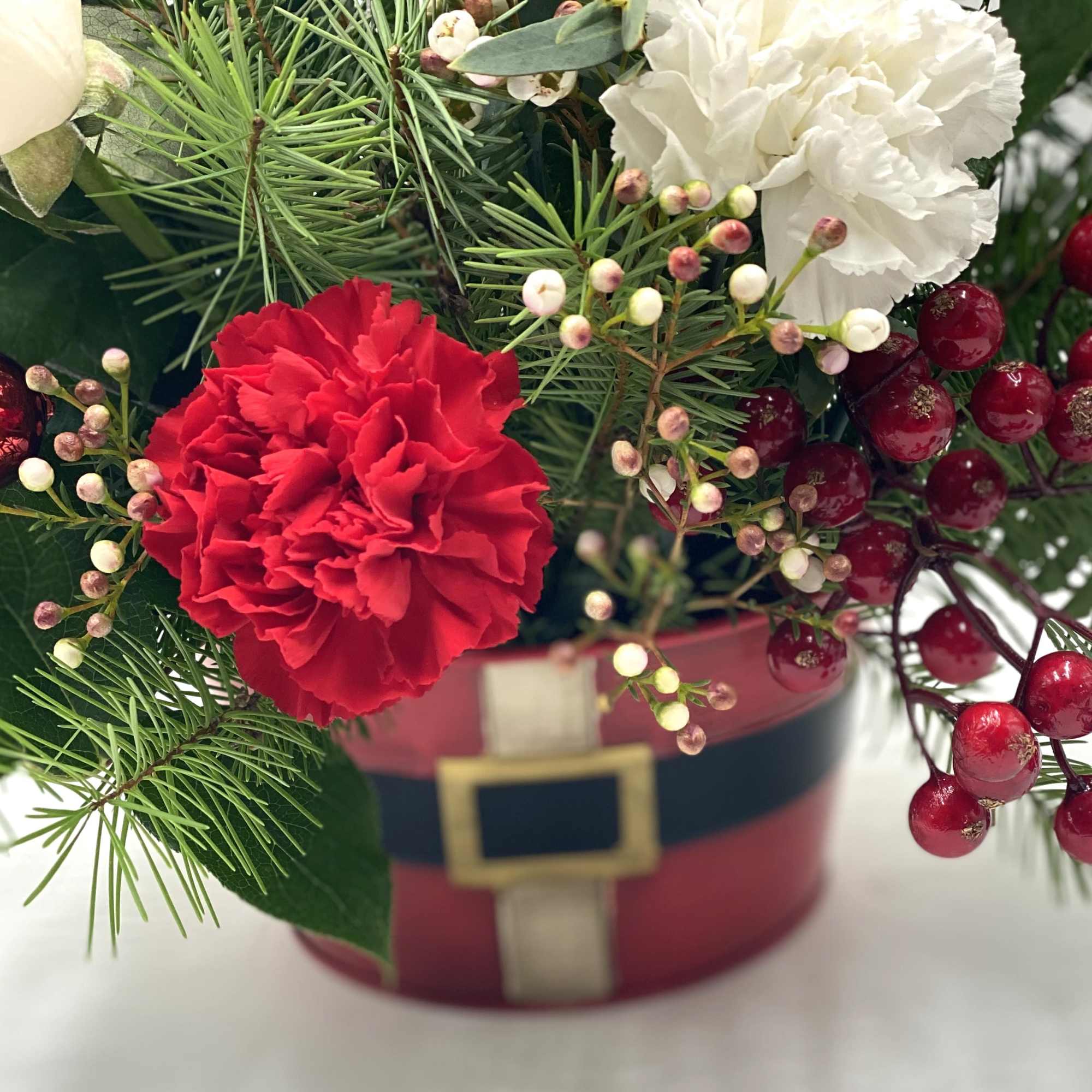 A festive holiday arrangement featuring rich red roses &amp; carnations paired with
