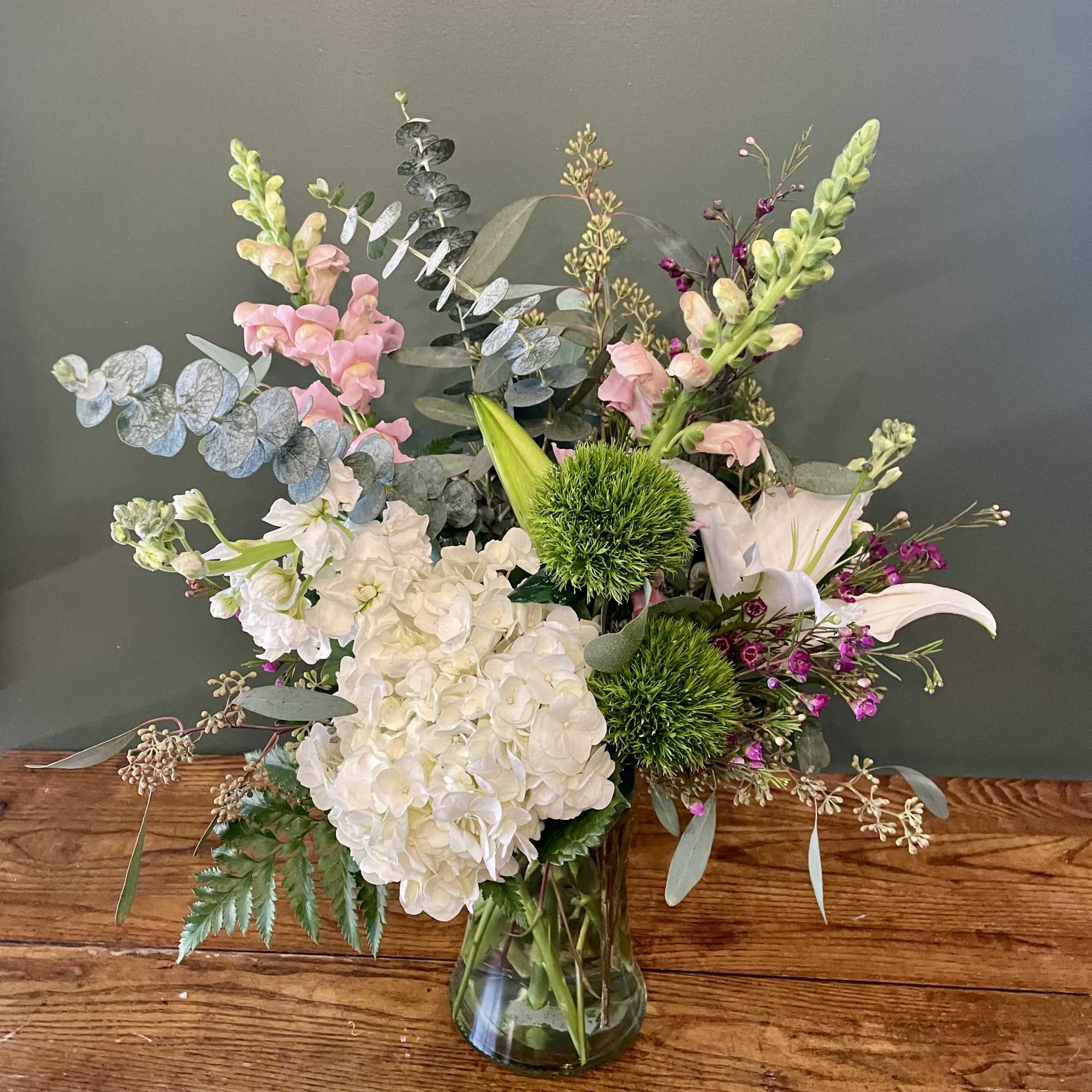 Beautiful floral arrangement in a clear vase with lilies, hydrangeas, snapdragon, green