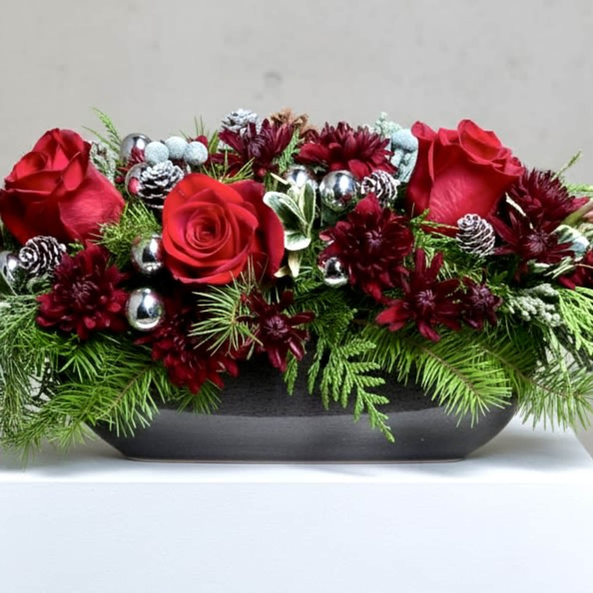 Long and narrow centerpiece of evergreen, Burgundy Mums, Red Roses,  pinecones