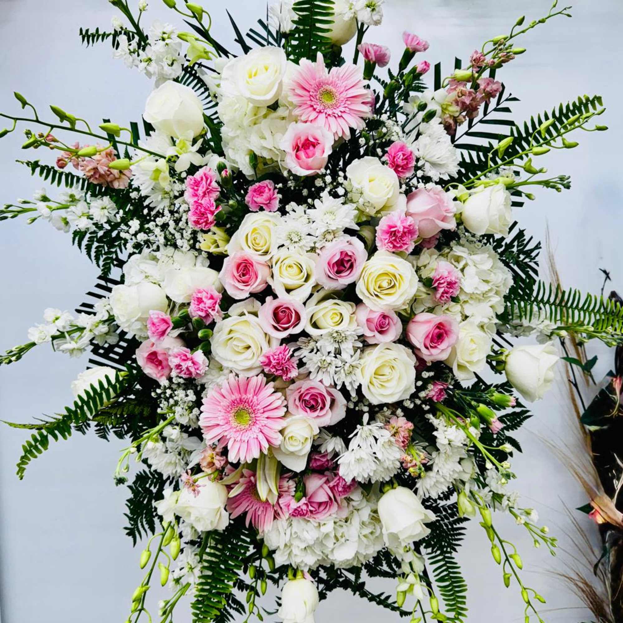 Artfully arranged pink and white florals create a captivating standing spray to