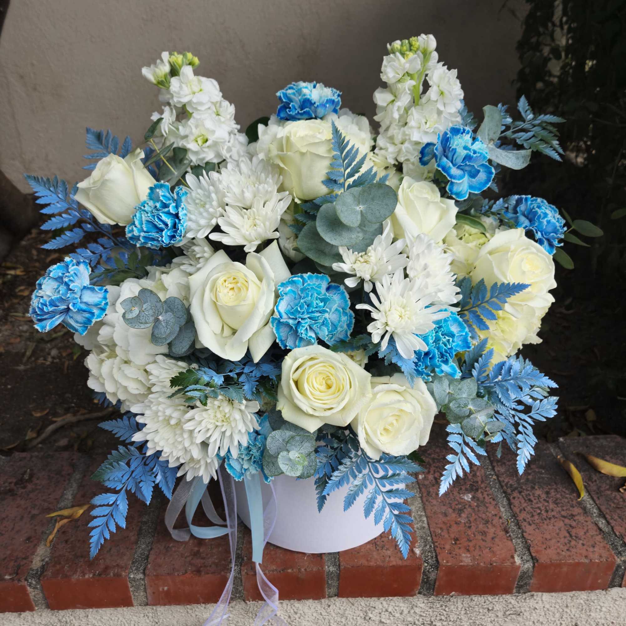 This flower arrangement features a stunning combination of white roses, white chrysanthemums