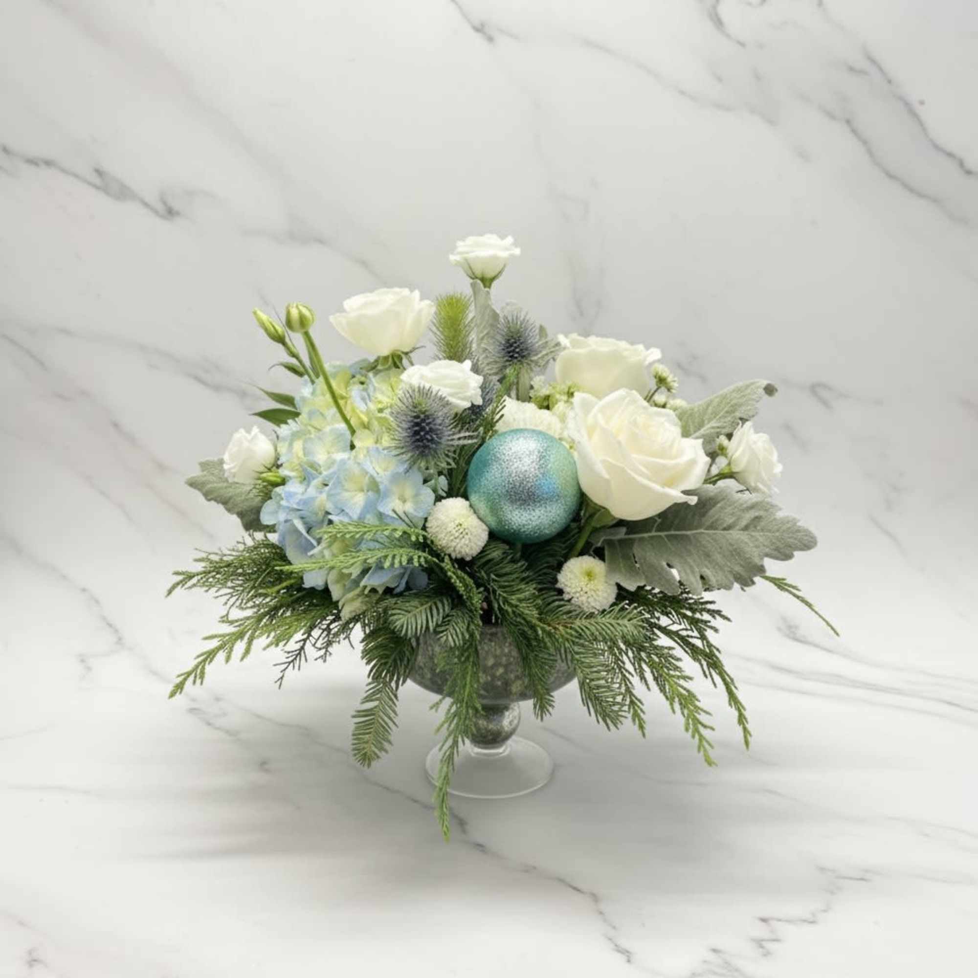 A clean ,winter-inspired arrangement featuring white rose, soft blue flowers, and fresh