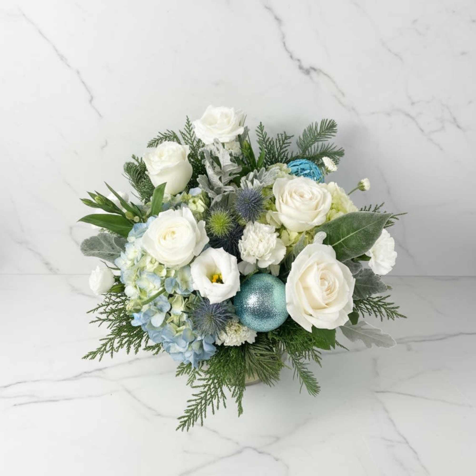 A clean ,winter-inspired arrangement featuring white rose, soft blue flowers, and fresh
