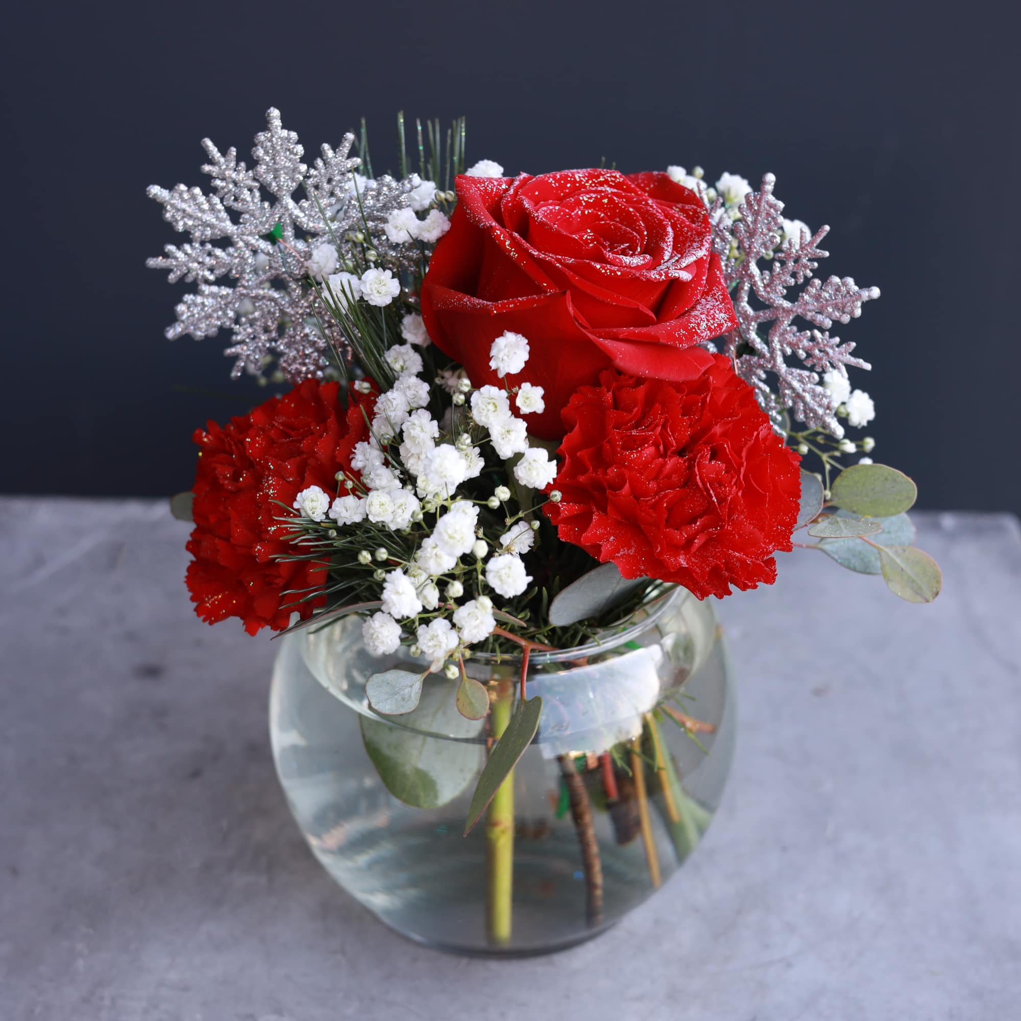 A sweet small arrangement exploding with style, glitter, and holiday decoration! Bring