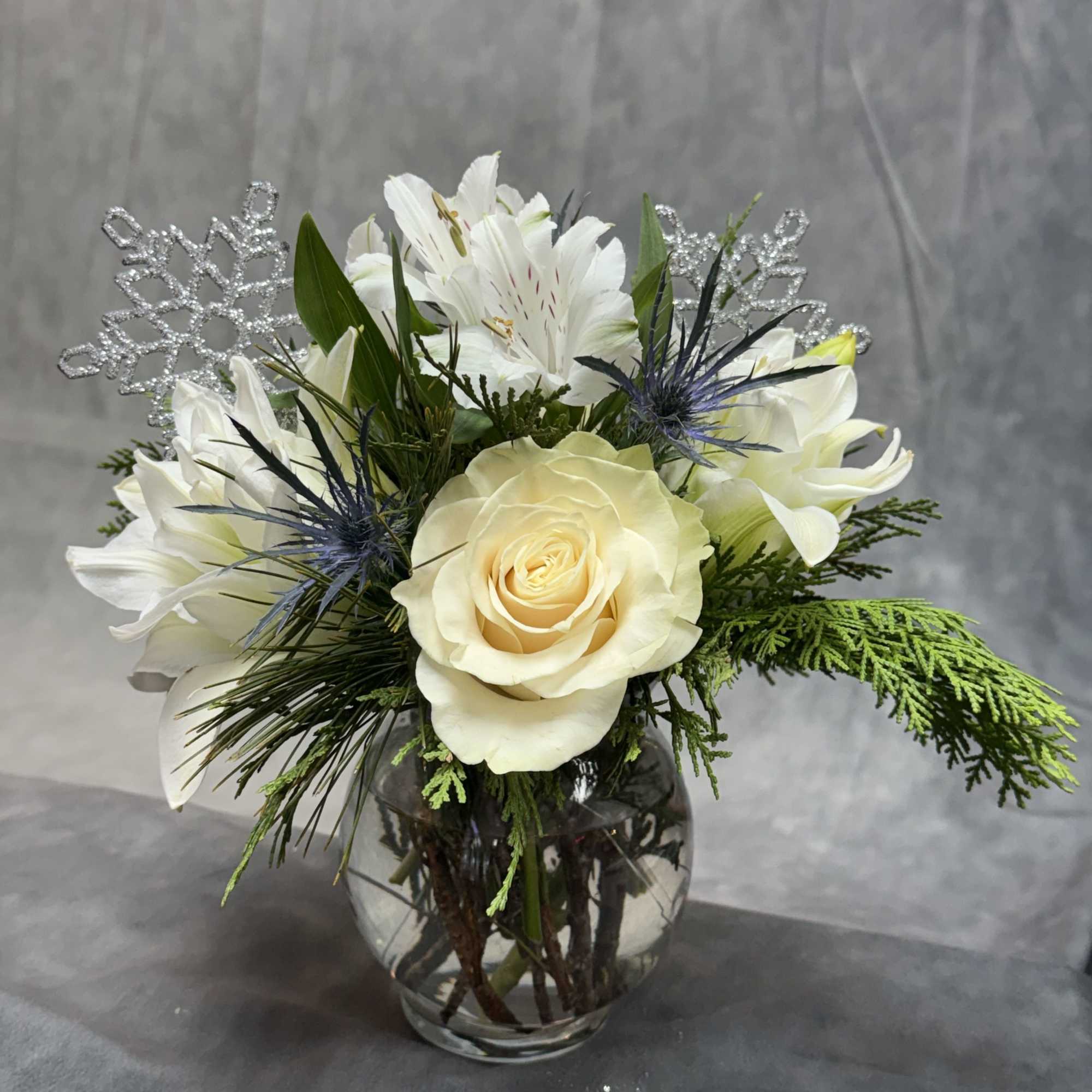 A timeless winter arrangement featuring creamy white roses, delicate alstroemeria, frosted accents