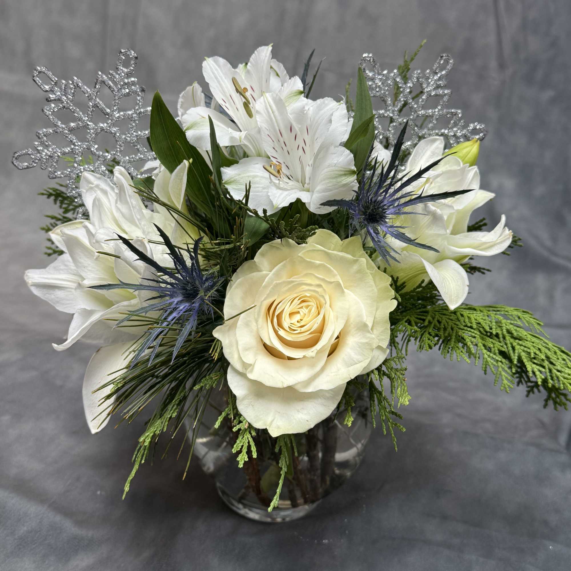 A timeless winter arrangement featuring creamy white roses, delicate alstroemeria, frosted accents