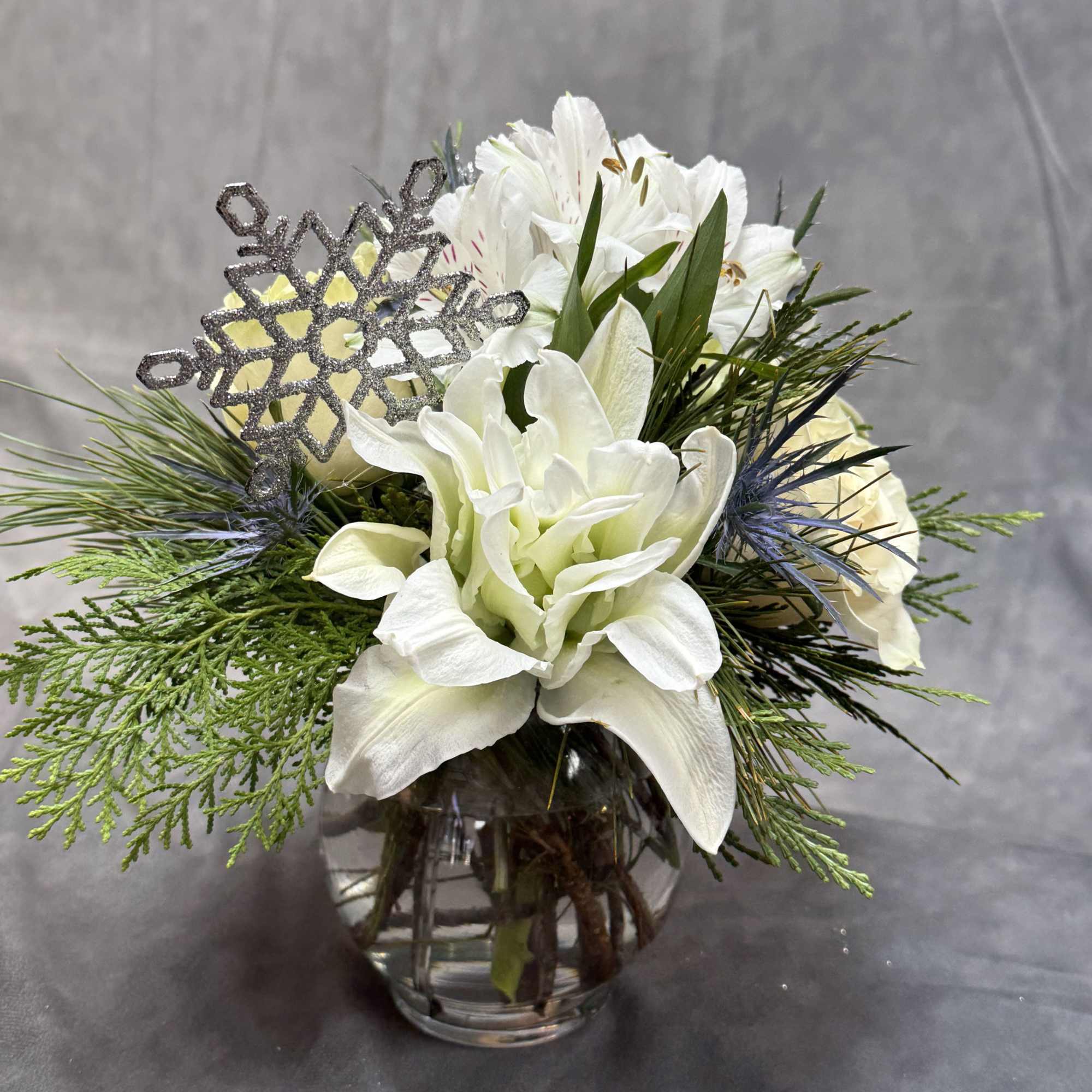 A timeless winter arrangement featuring creamy white roses, delicate alstroemeria, frosted accents