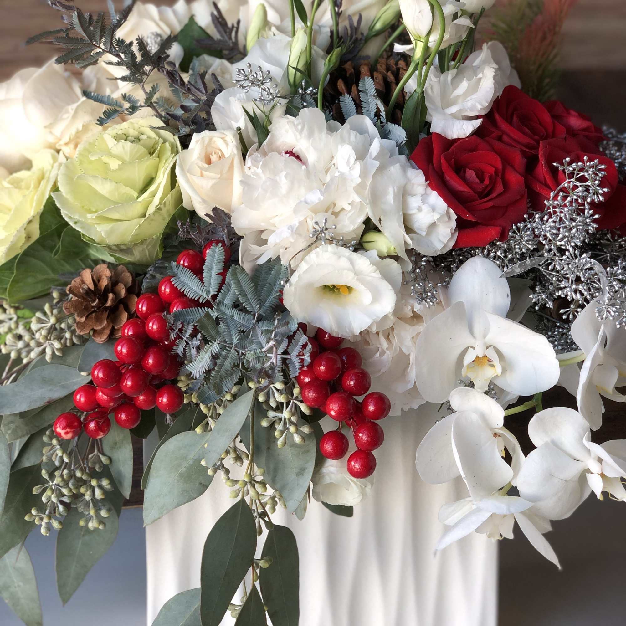 An abundance of holiday greens accented berry decorations, lush red roses, white