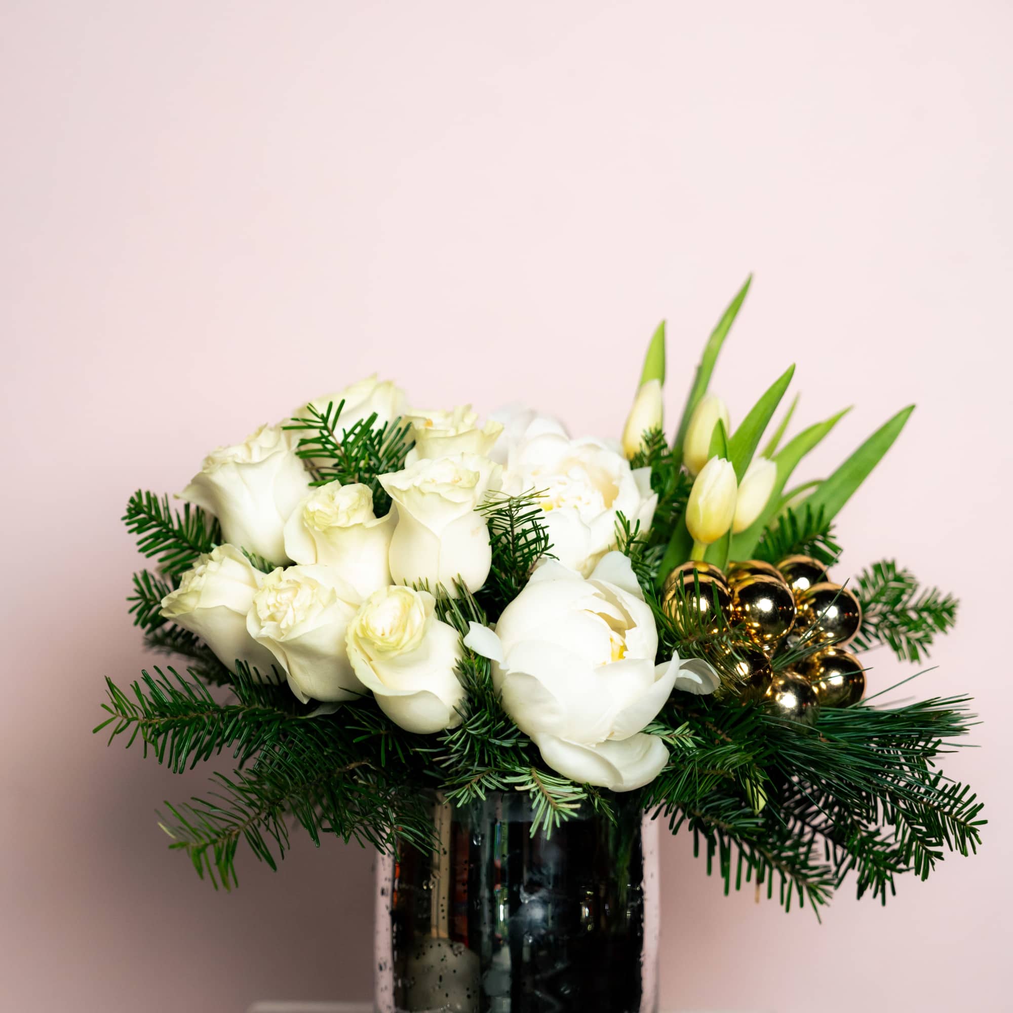White roses, peonies and assorted white florals among holiday greens and ornaments