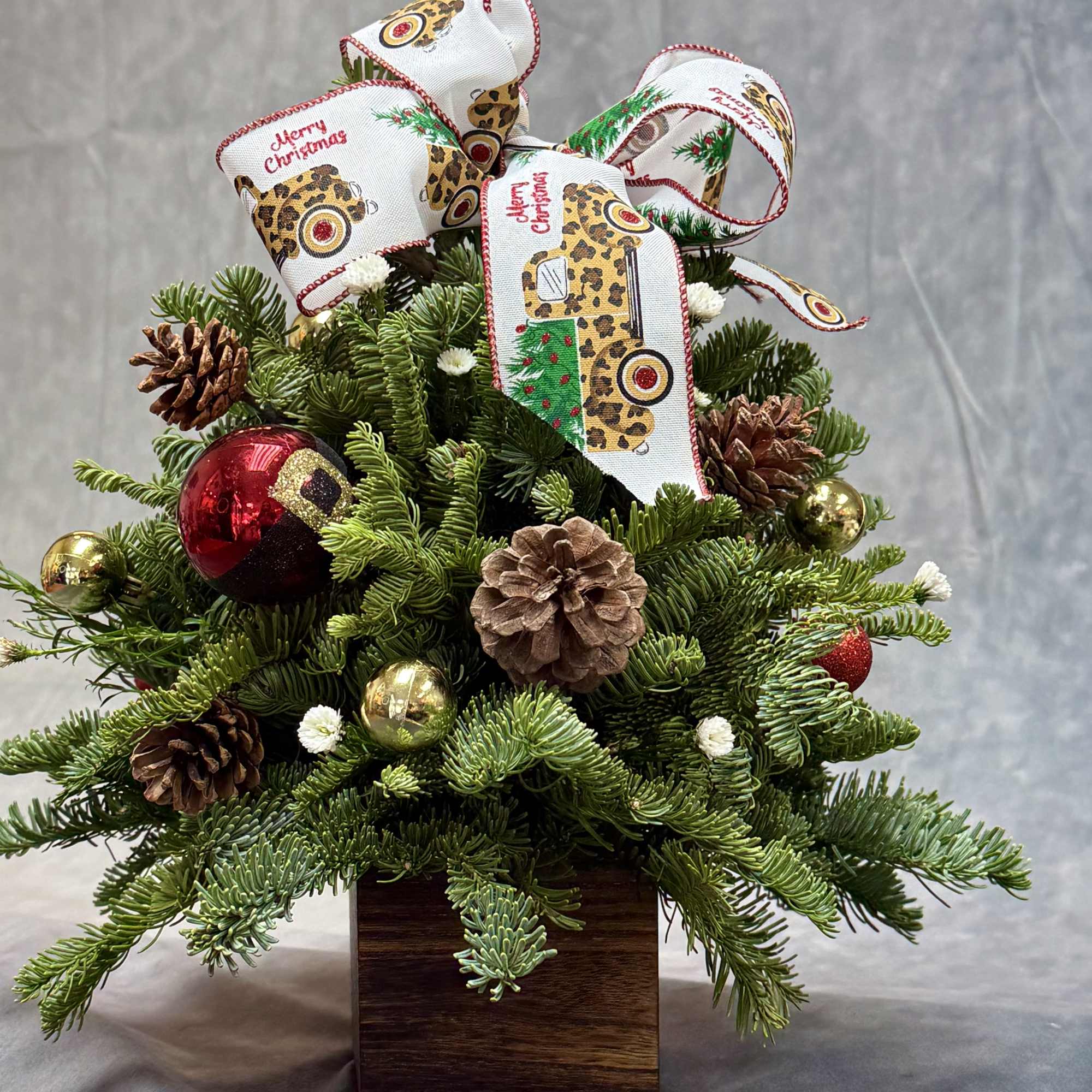A charming Christmas tree box designed with fresh evergreen greenery, pinecones, festive