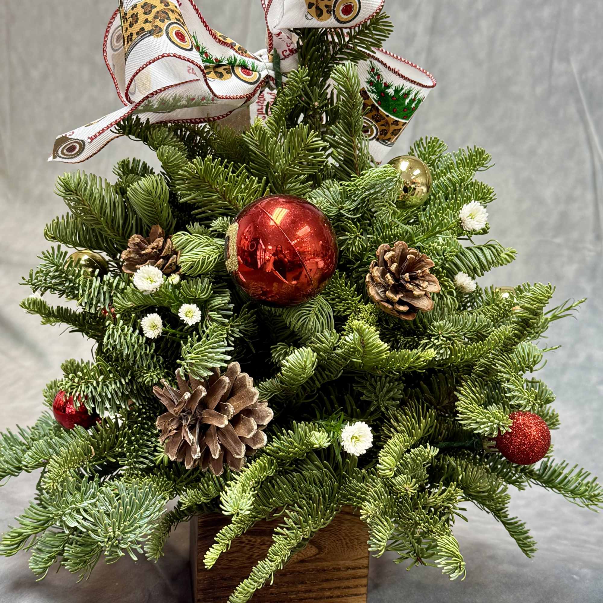 A charming Christmas tree box designed with fresh evergreen greenery, pinecones, festive