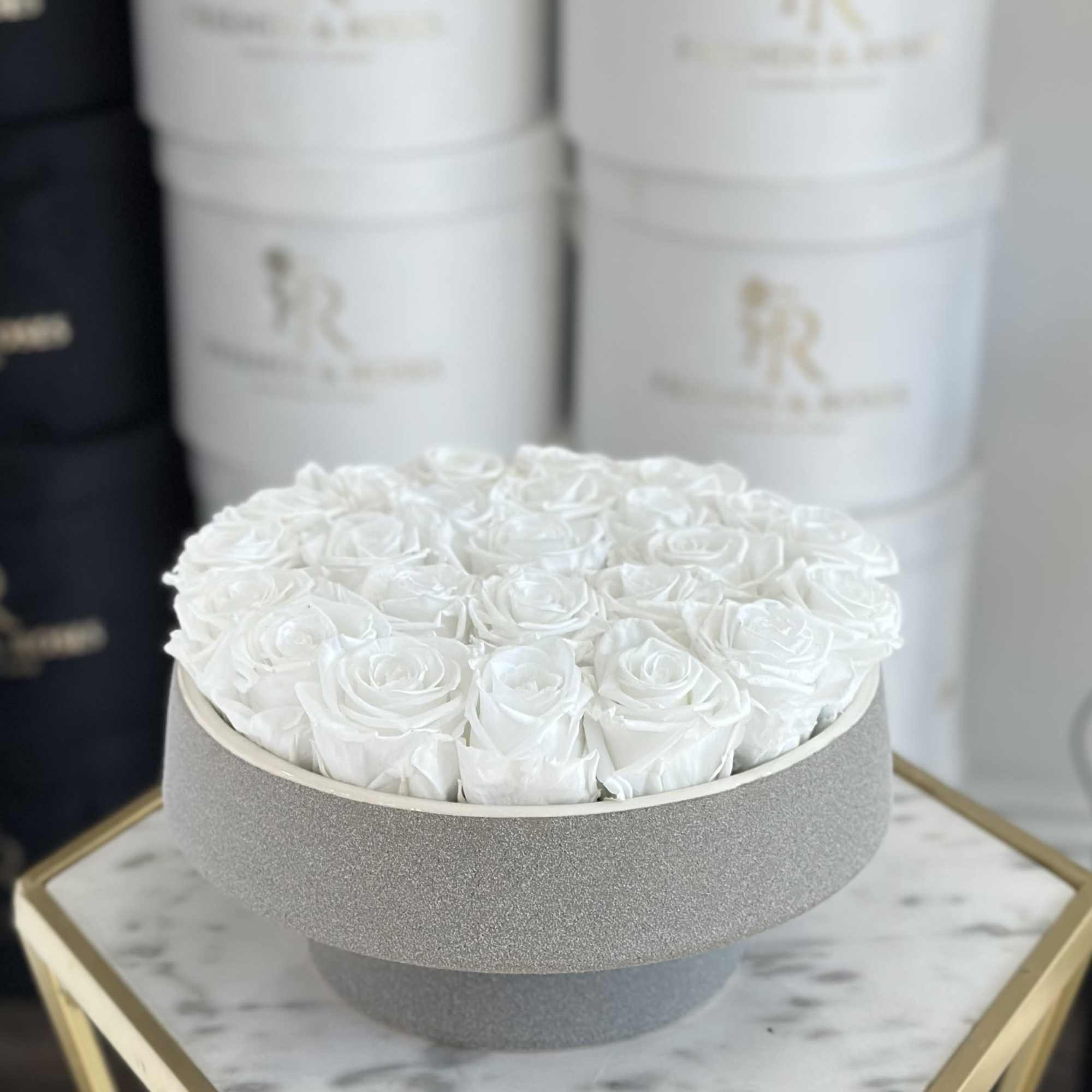 Elegant round vase featuring approximately 25 white eternal roses - a refined