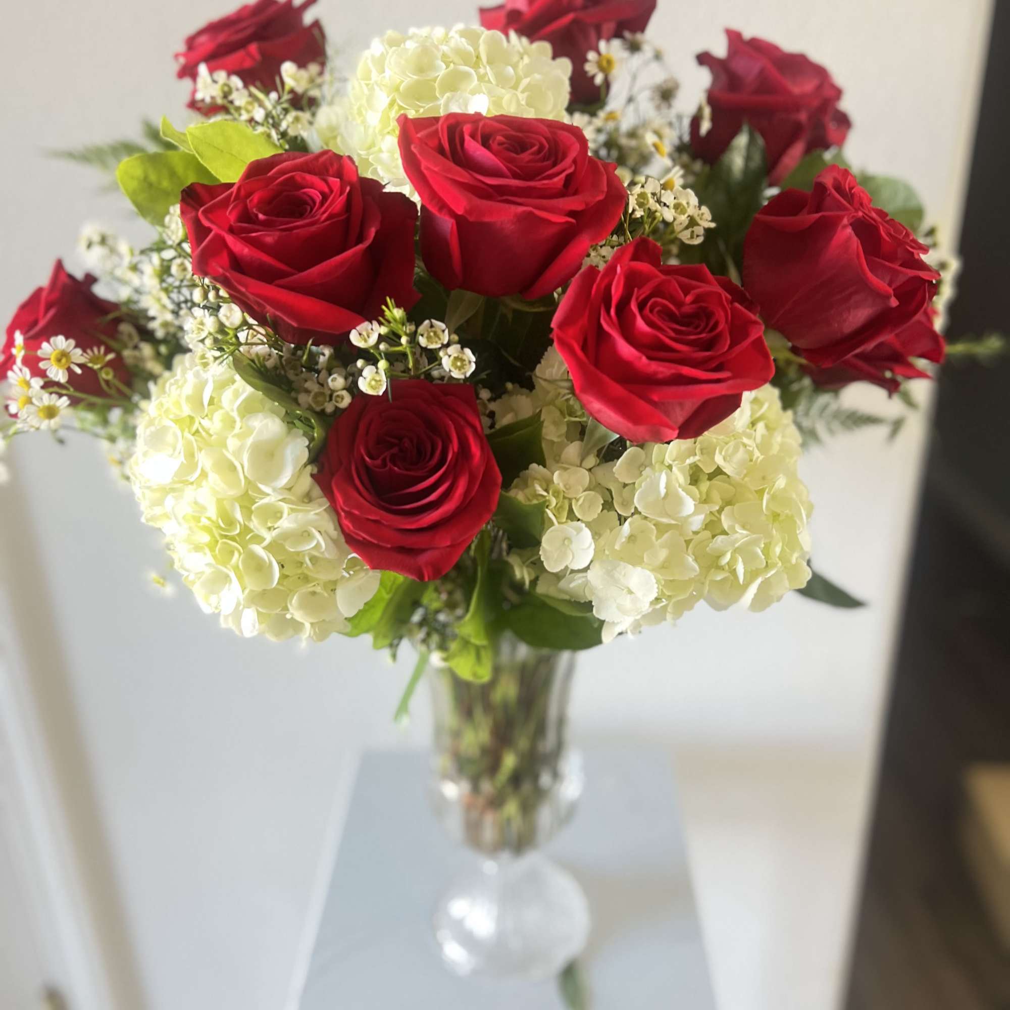 This stunning arrangement features one dozen premium red roses, beautifully complemented by
