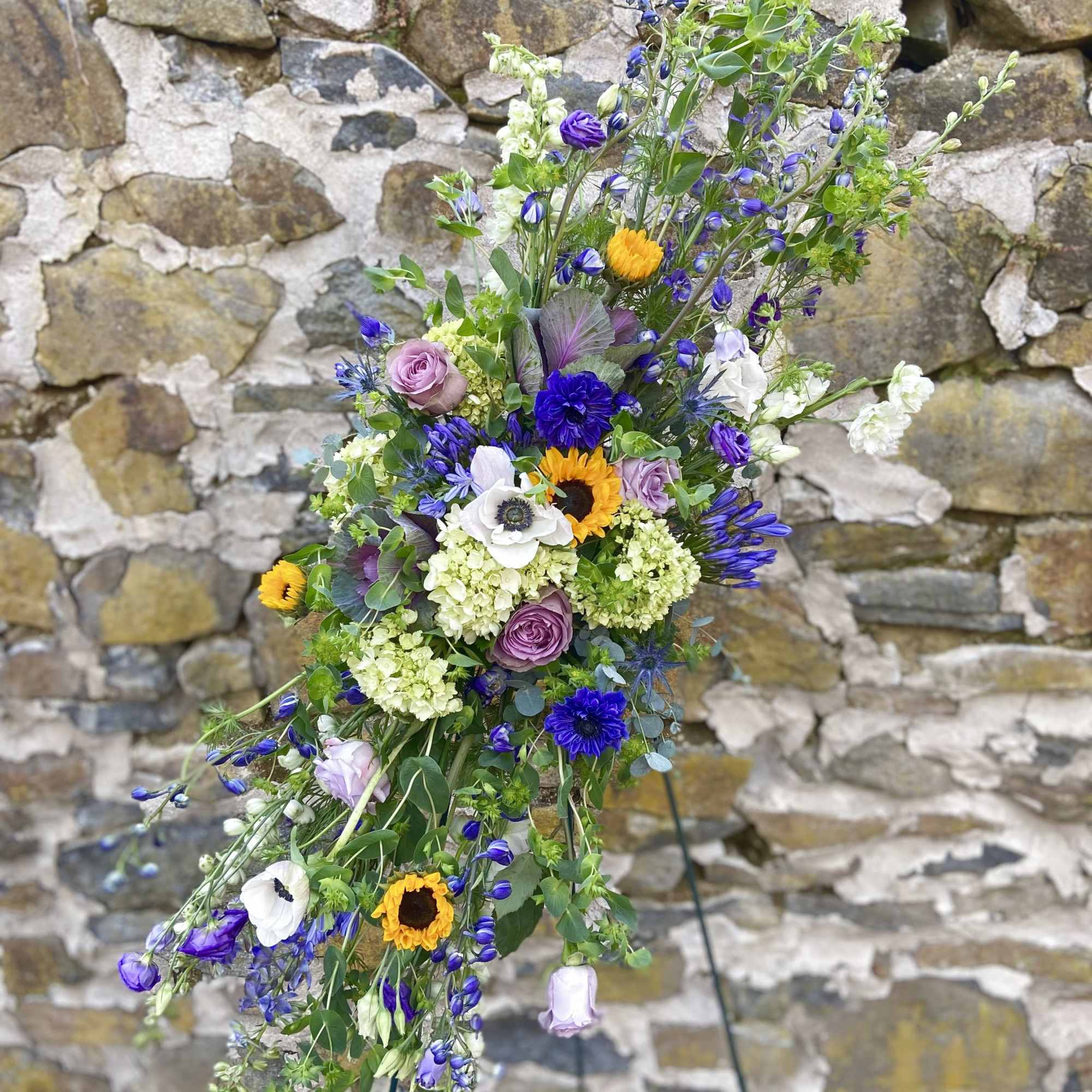 Seasonal florals and greenery reach towards the heavens to memorialize your loved
