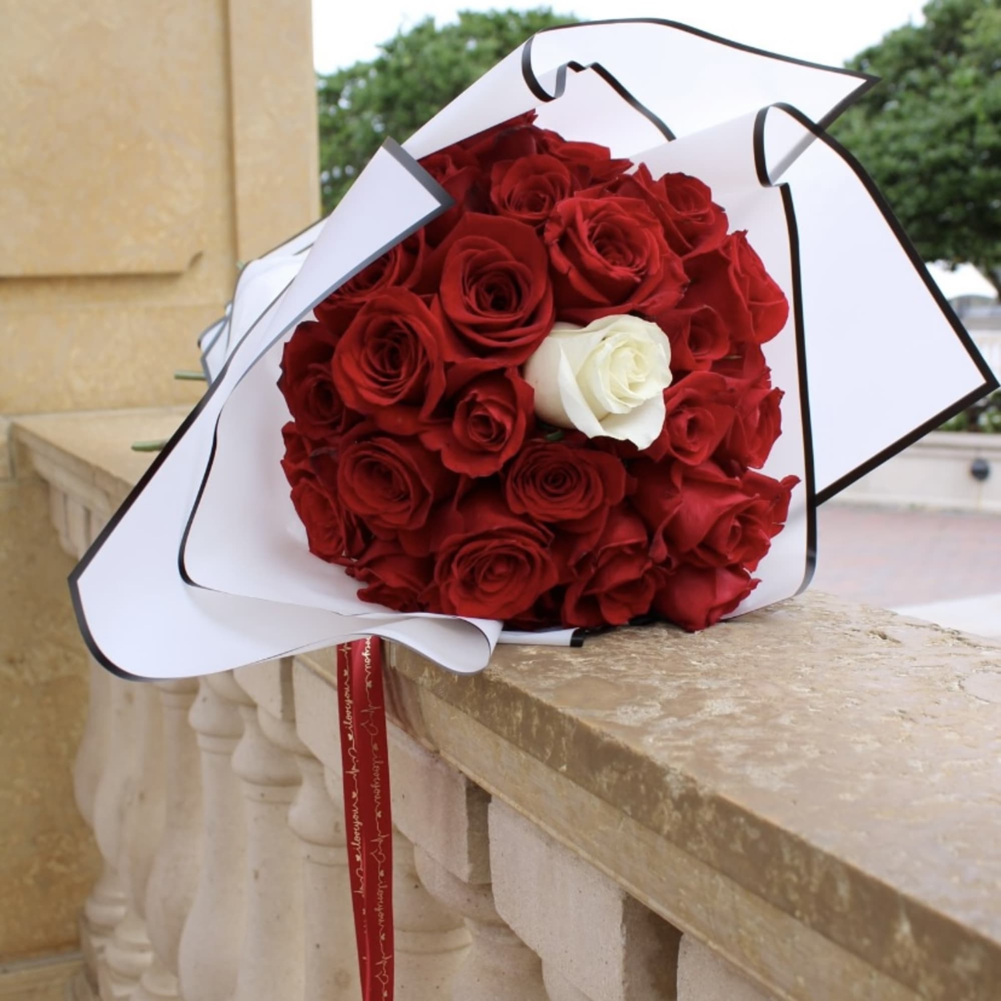 Red and white roses, wrapped in white and black paper Glass vase