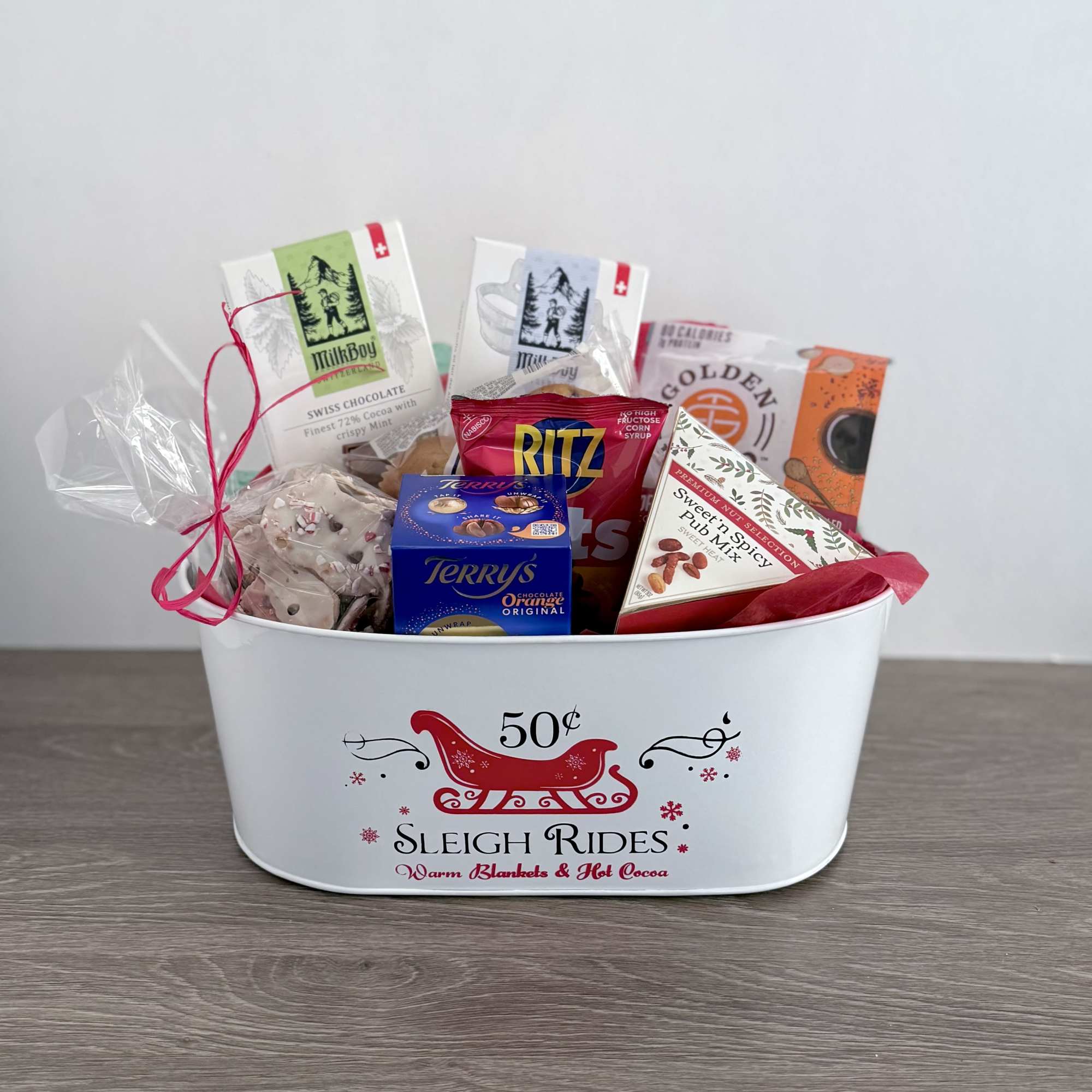 A metal sleigh ride container filled with a variety of snacks. Swissboy