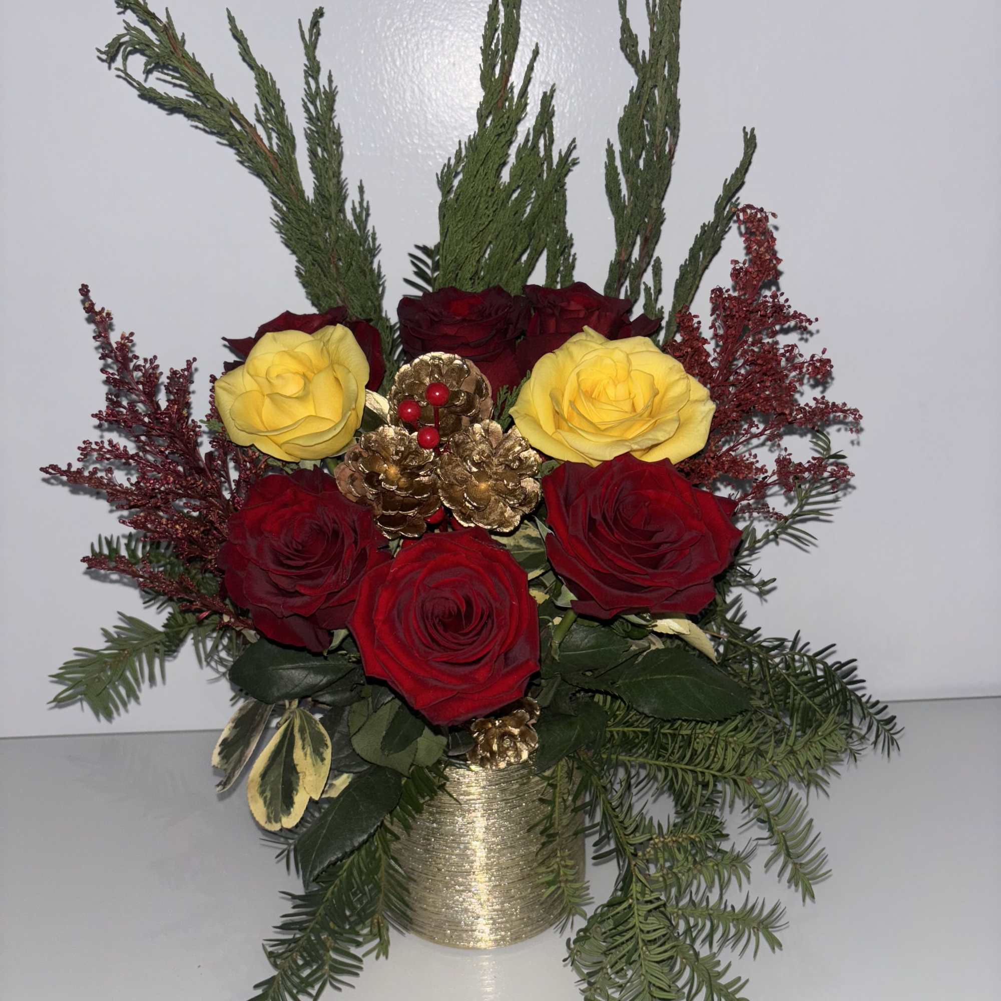 Decorations: Small gold-painted pinecones and a cluster of gold berries are nestled