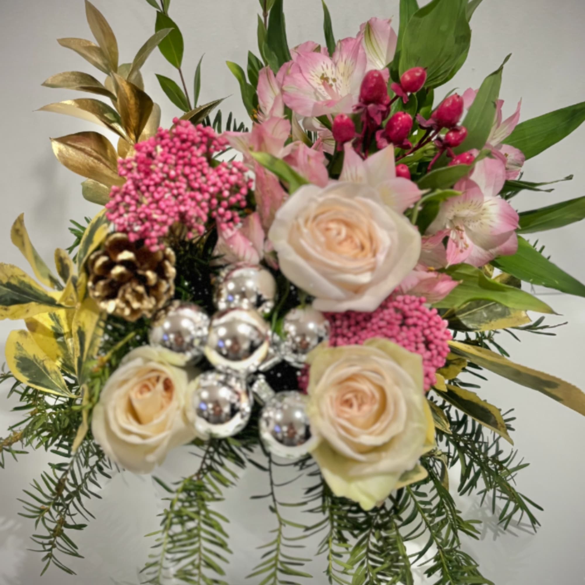 A refined festive floral arrangement featuring soft pink and cream roses, pink