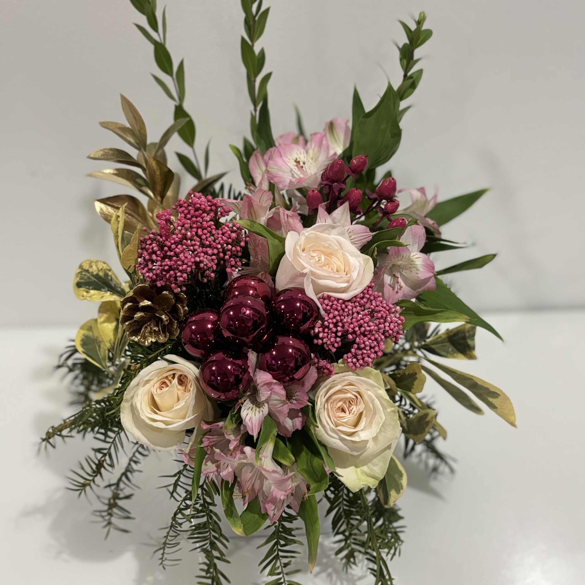 A refined festive floral arrangement featuring soft pink and cream roses, pink