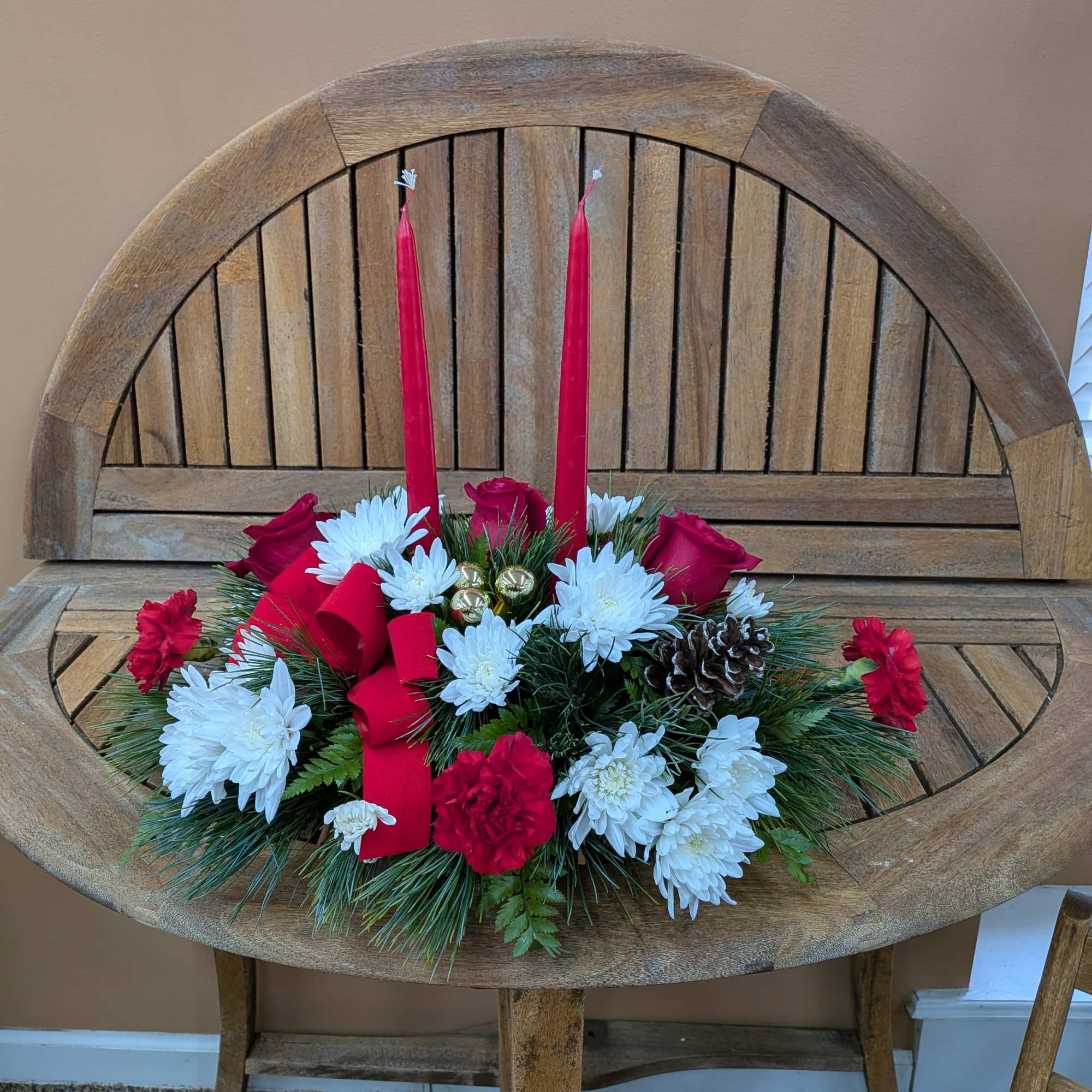 Centerpiece with red candle, red ribbons, pinecones, red roses, red carnations and
