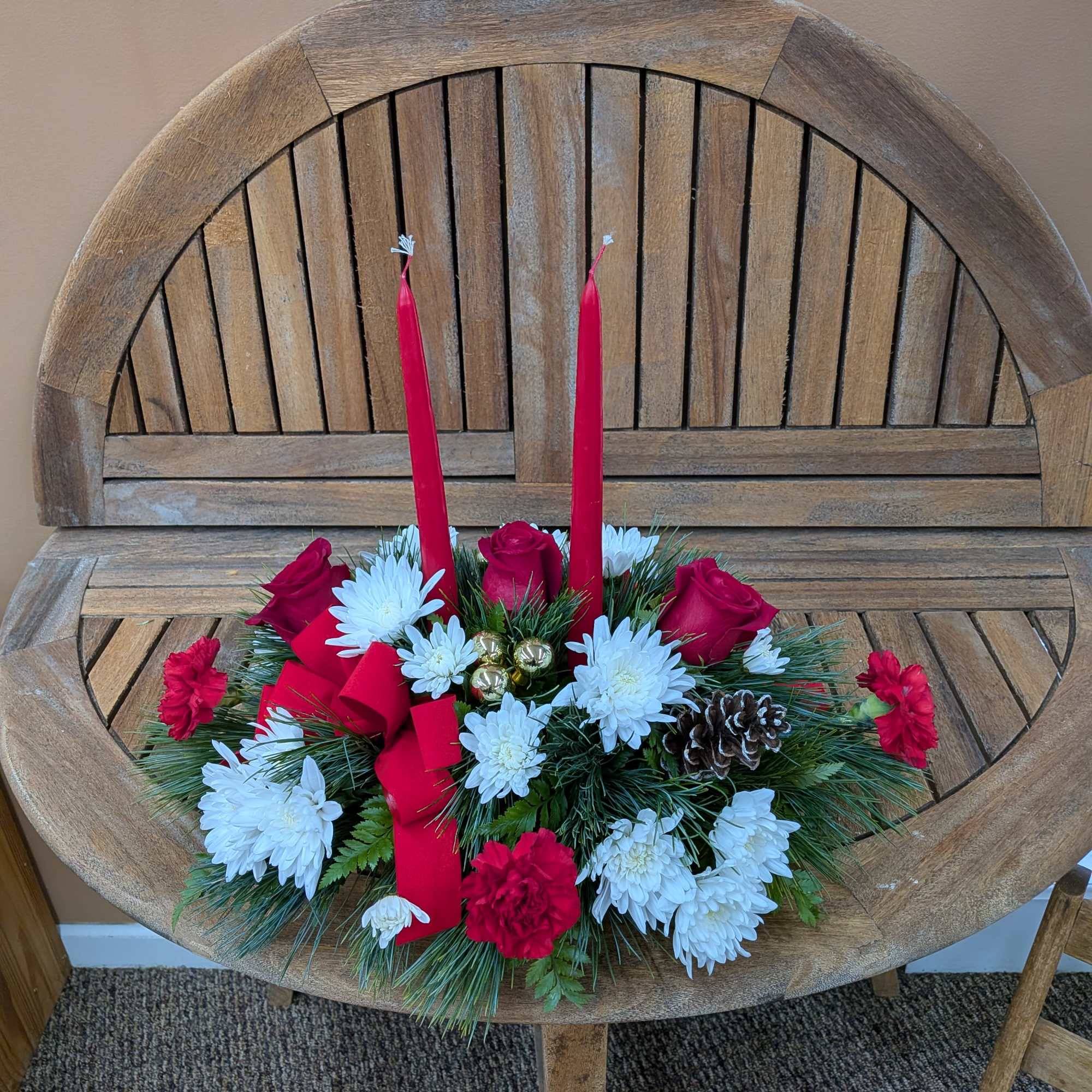Centerpiece with red candle, red ribbons, pinecones, red roses, red carnations and
