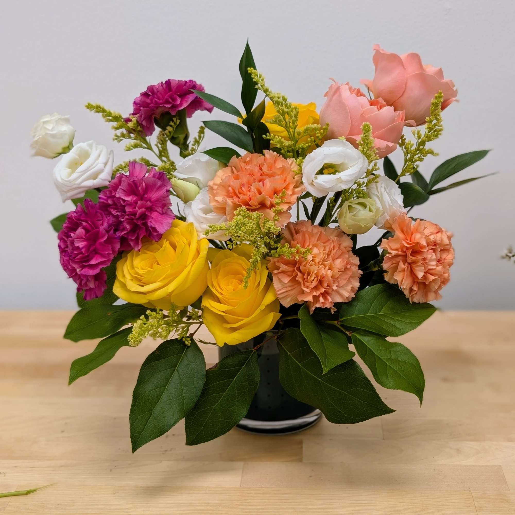 This cheerful arrangement is a vibrant explosion of summer hues, expertly blending