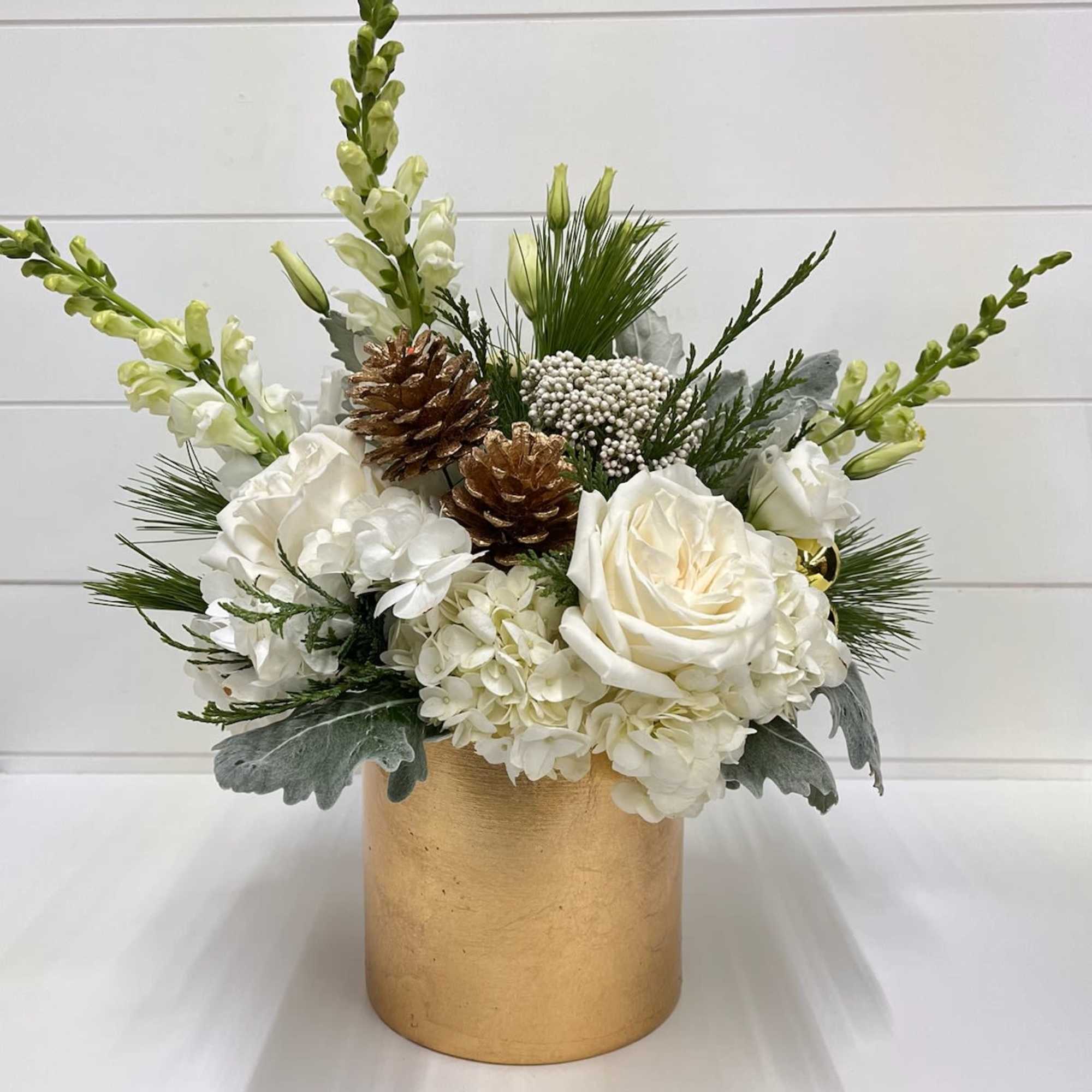 Elegant holiday floral arrangement featuring white roses and hydrangeas, accented with winter