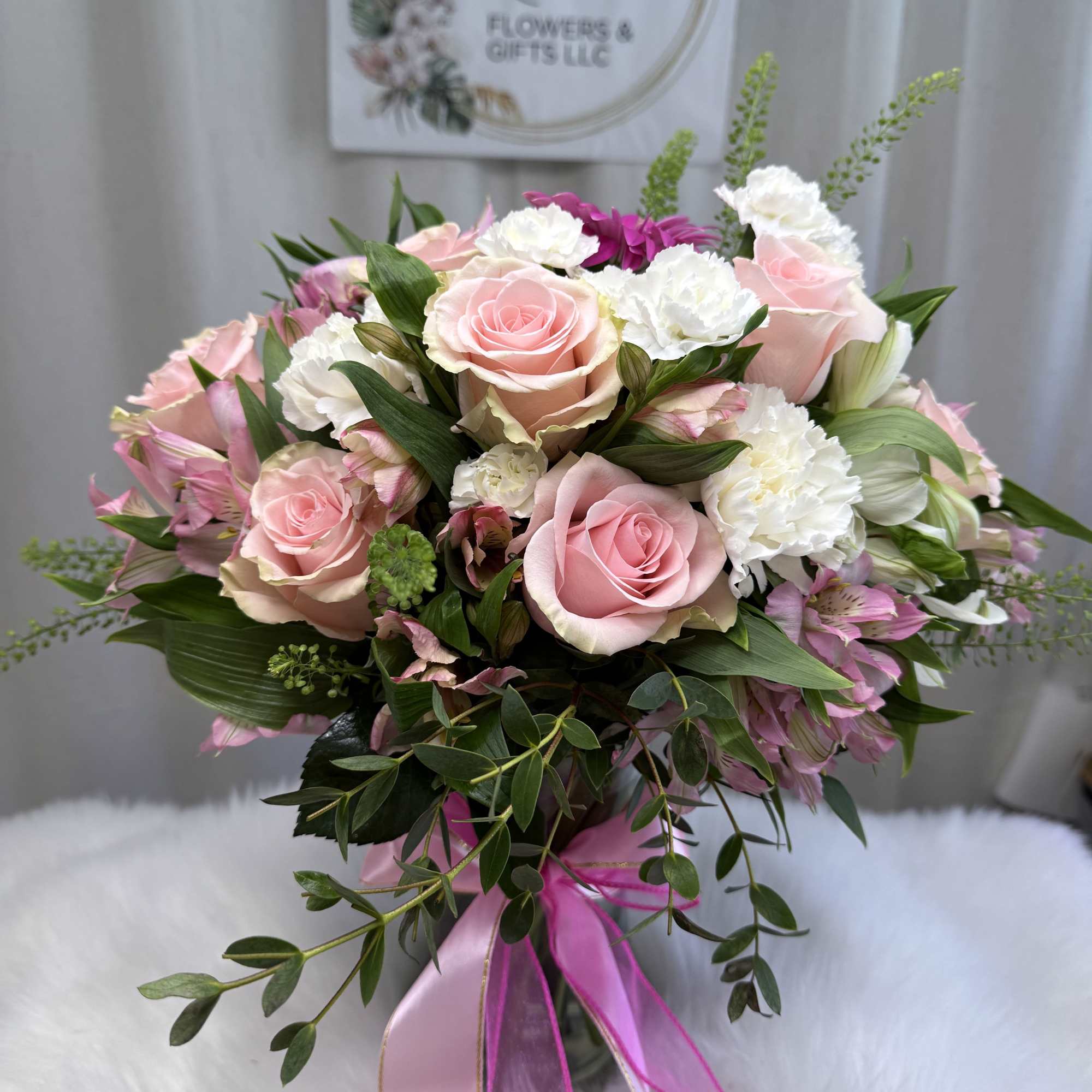 This stunning arrangement features soft pink roses, delicate white carnations, and fresh