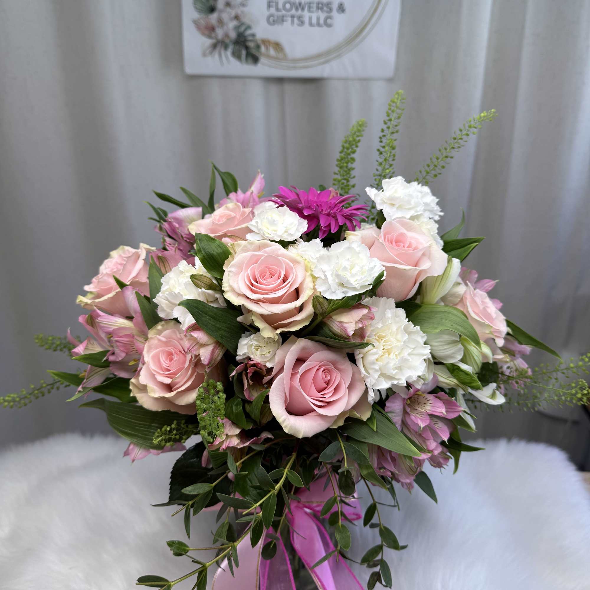 This stunning arrangement features soft pink roses, delicate white carnations, and fresh