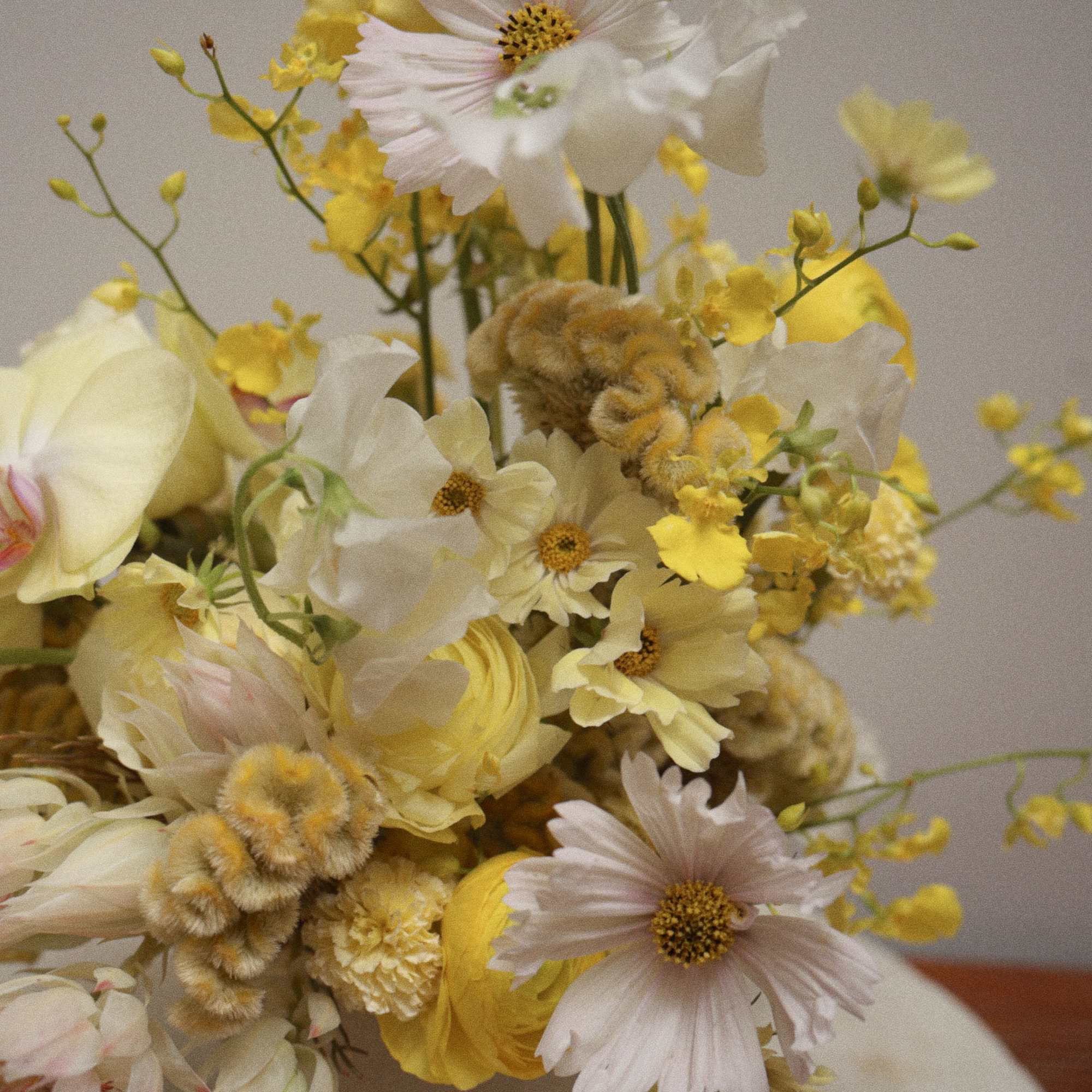 An all-yellow floral arrangement designed with a clean, modern aesthetic. 
Featuring seasonal